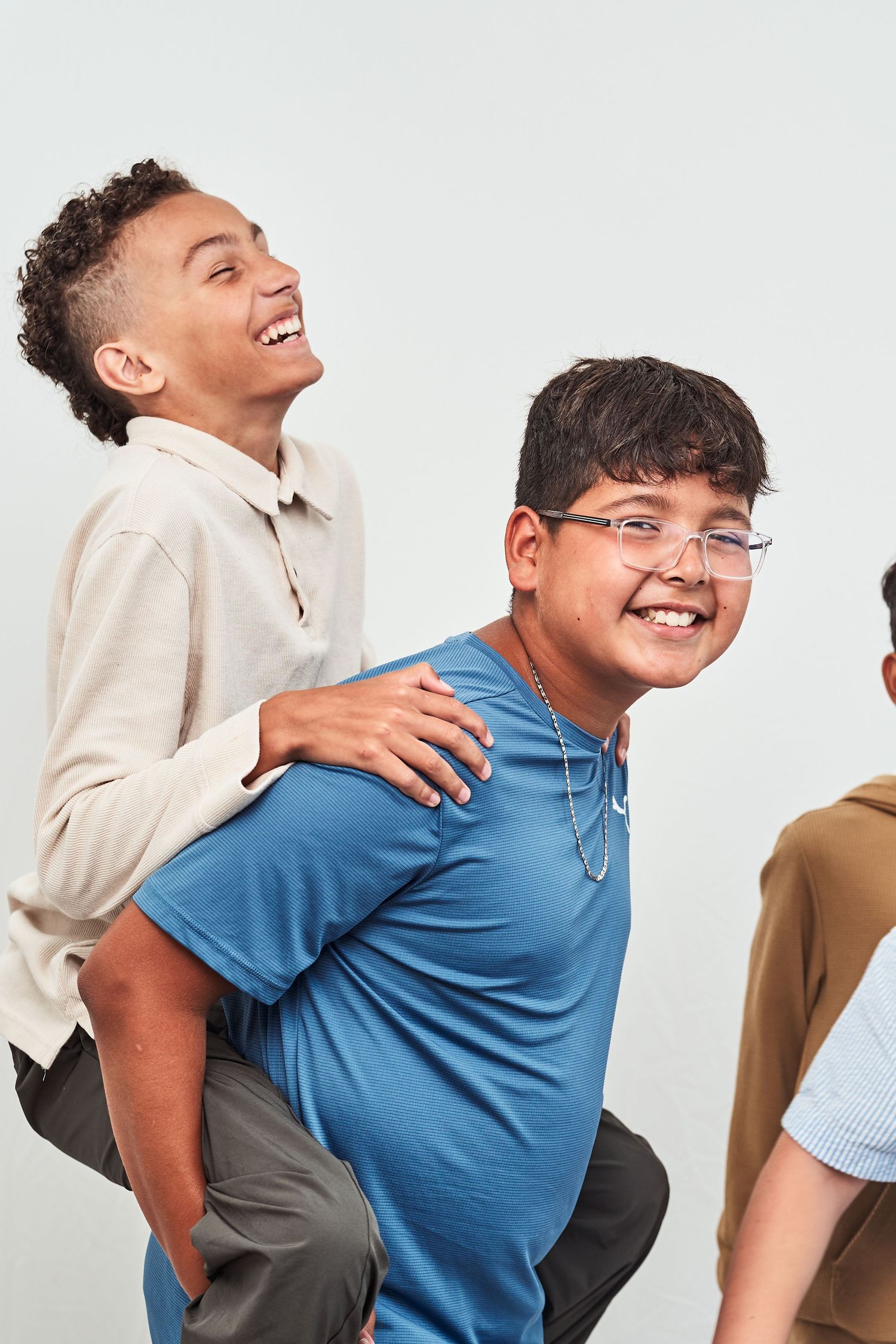 Two people wearing blue and beige clothing laughing and interacting while posing for playful photos.