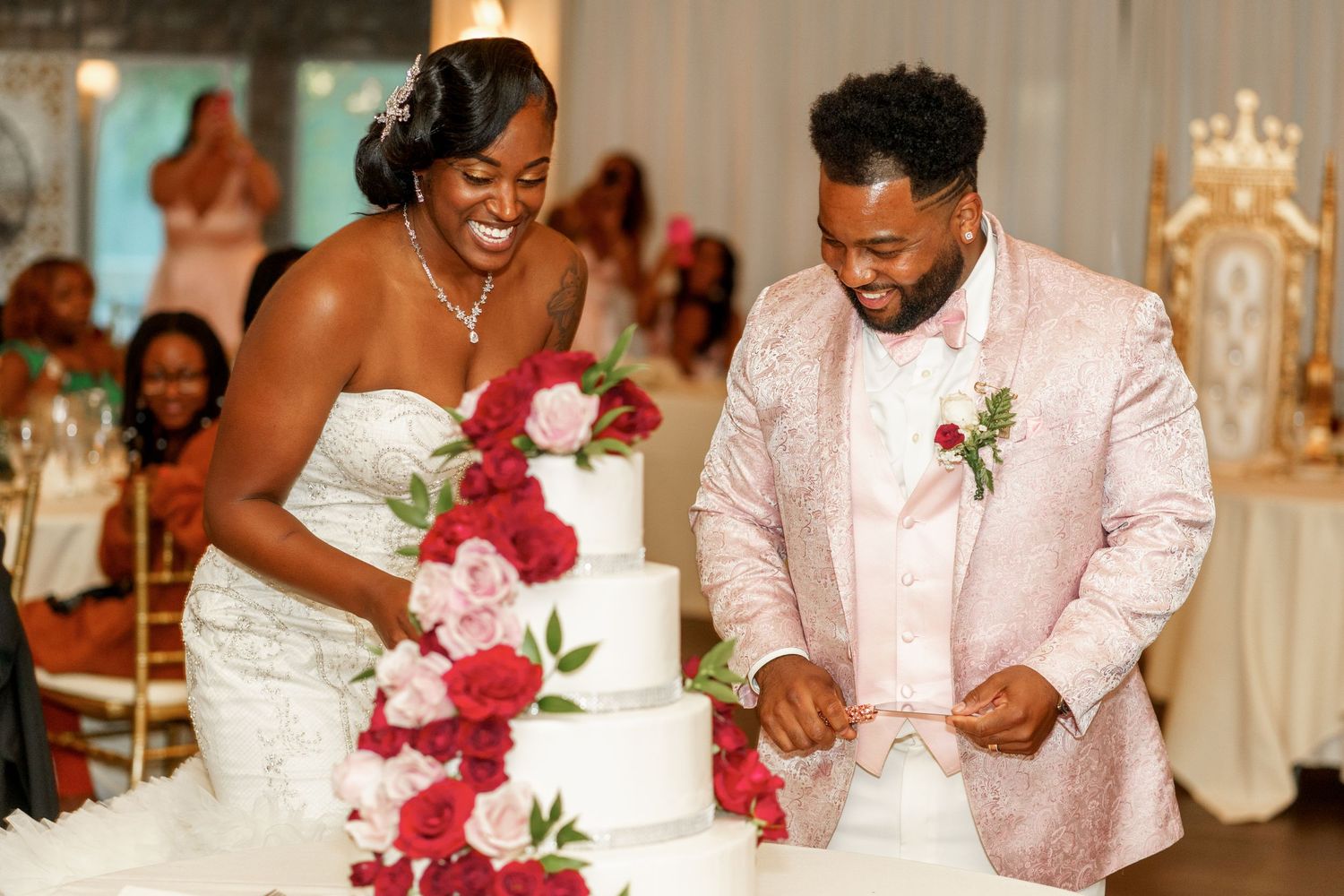 Couple cutting their elegant white and red wedding cake during reception.