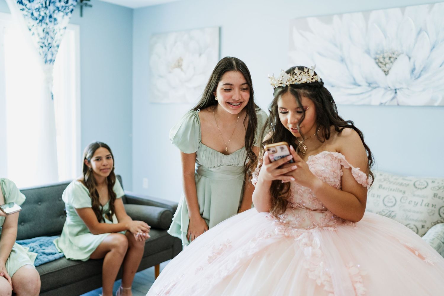 Friends in pastel dresses gather in a blue and white decorated room during a celebration.