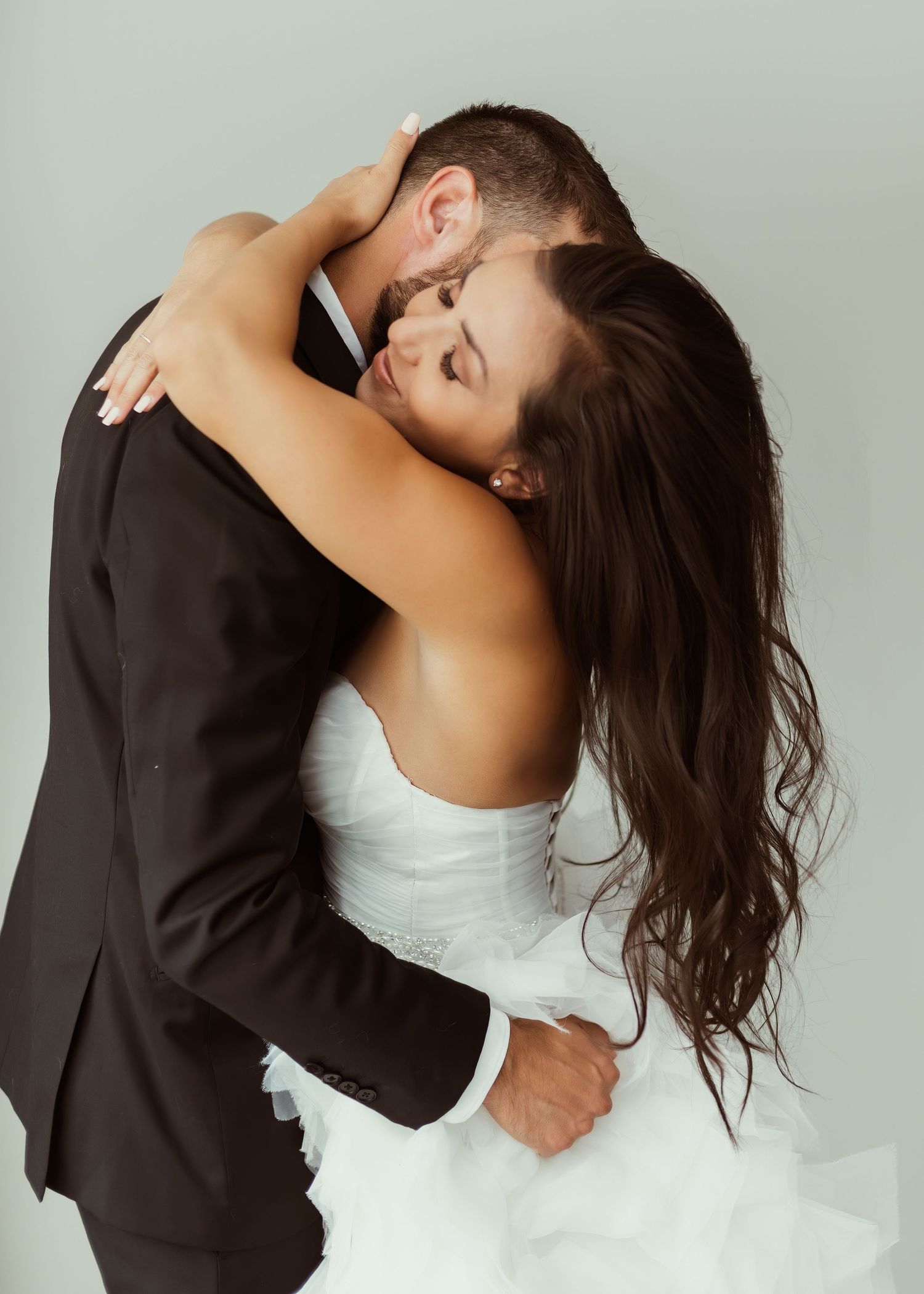 An artistic wedding photo showing a passionate embrace between newlyweds against a minimalist background.