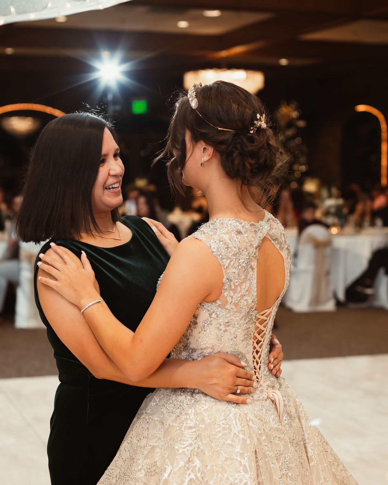 Two people share a joyful moment during a wedding reception in an elegant ballroom setting.
