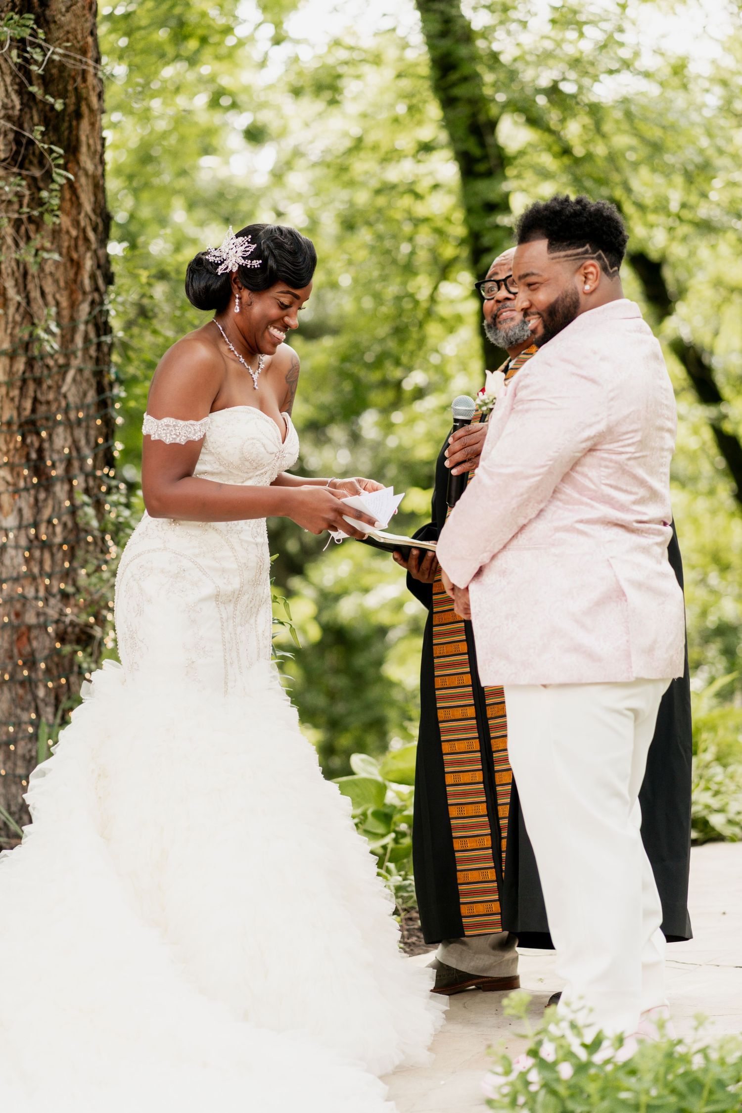 A couple exchanges vows during their outdoor wedding ceremony with an officiant in traditional robes.