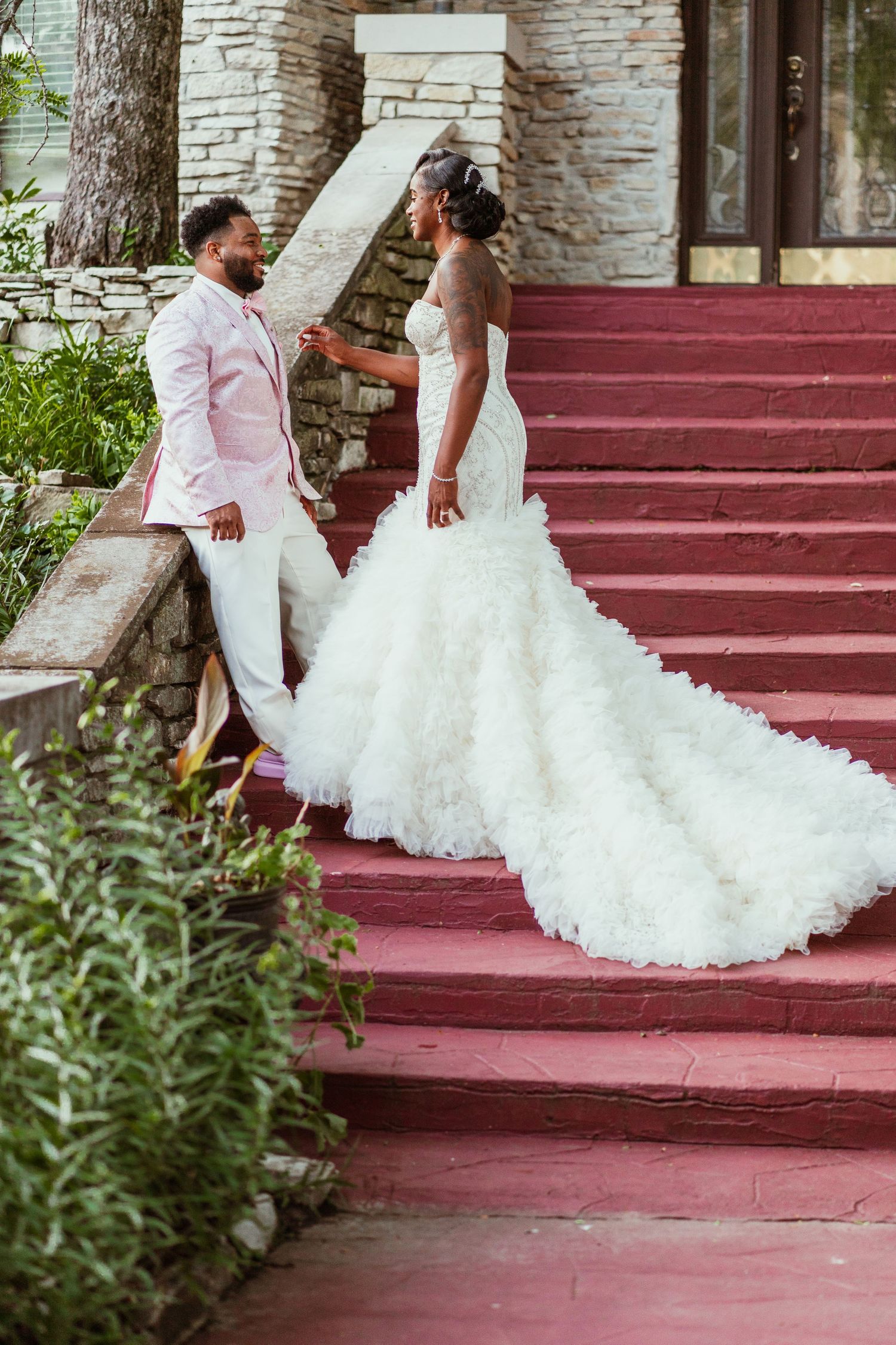 A beautiful wedding portrait on red stairs with a dramatic wedding gown train.