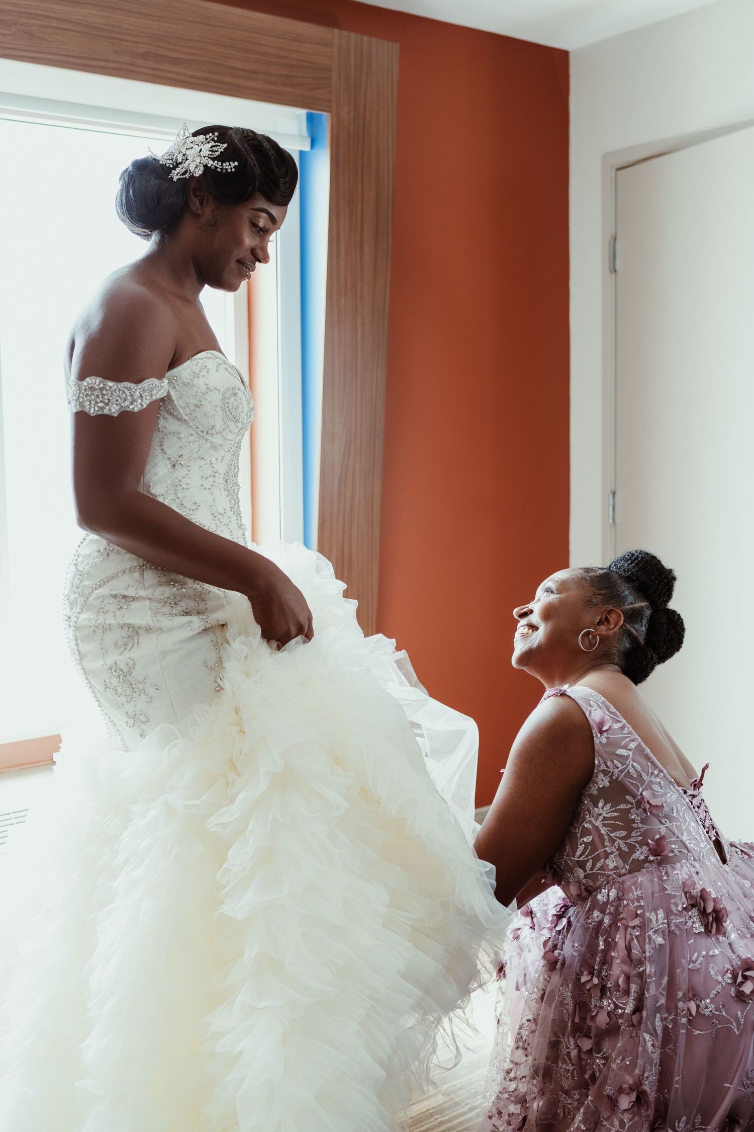An emotional moment during wedding preparations in a room with orange walls.