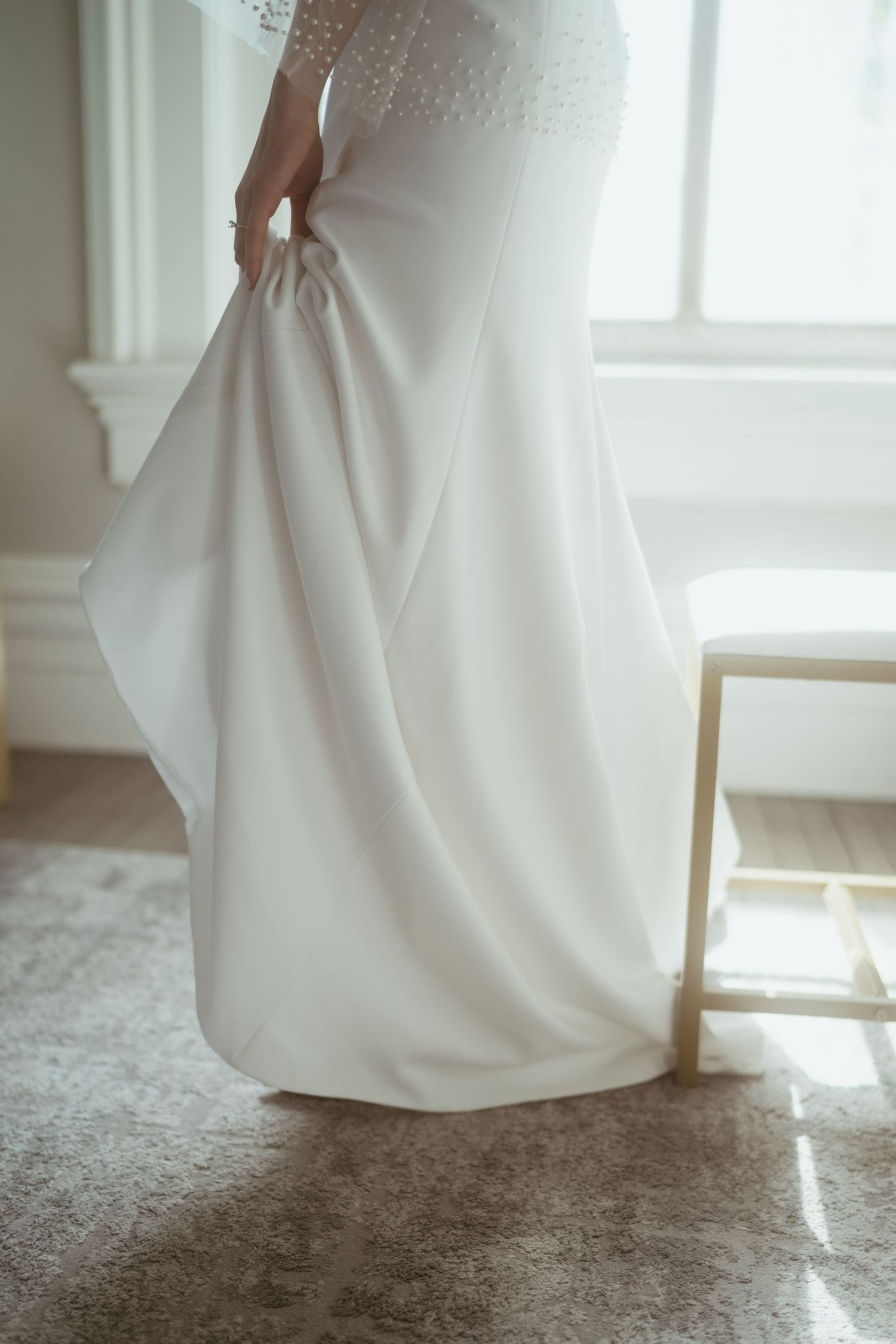 Close-up series of a flowing white wedding dress hem against a light carpet as sunlight streams through nearby windows.