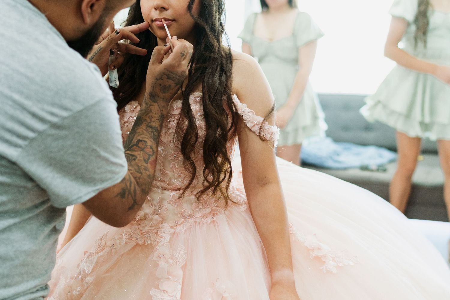 Makeup artist applies lipstick to a quinceanera wearing blush pink ballgown. | Quinceanera Getting Ready Photo | Munster, IN