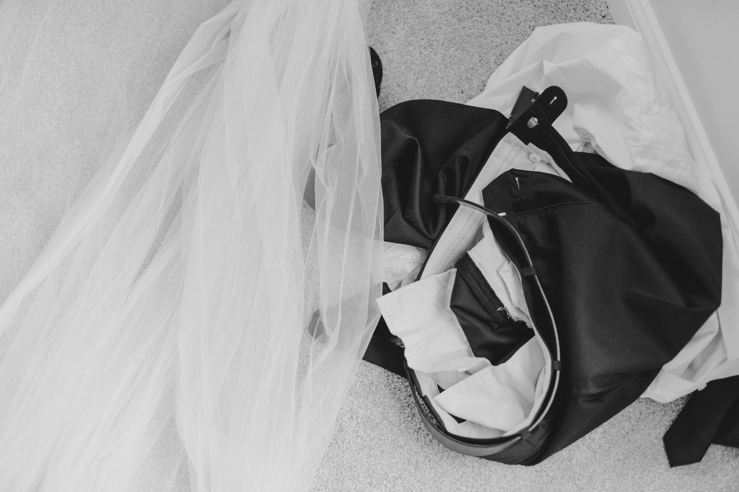 Black and white lingerie with a flowing white veil laid out on a surface.