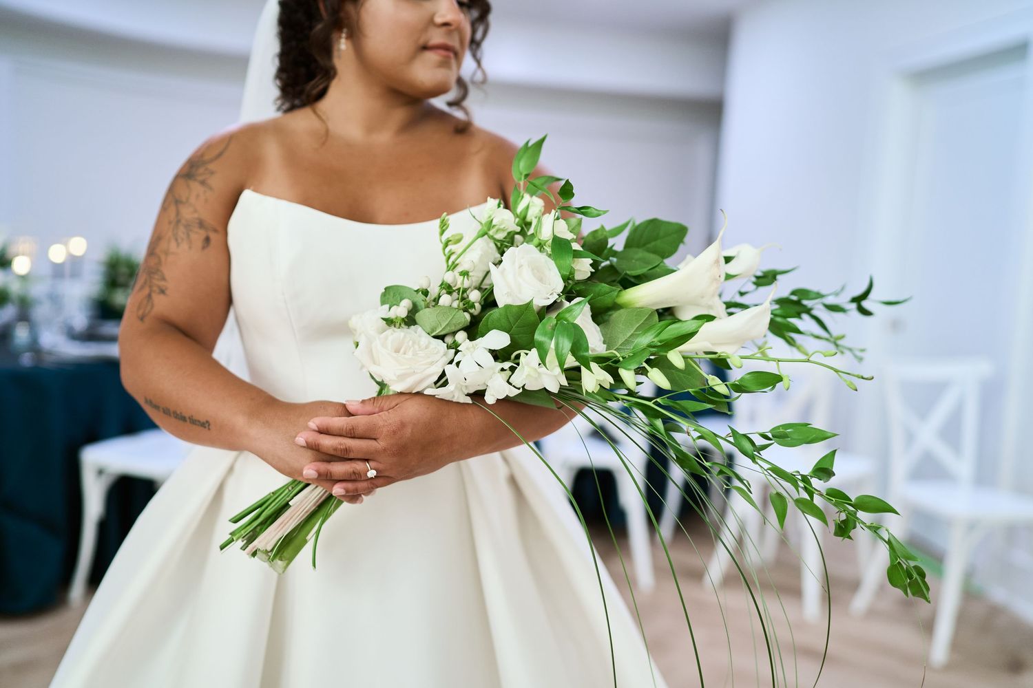 Elegant white bridal bouquet with cascading greenery and lilies against a wedding gown.