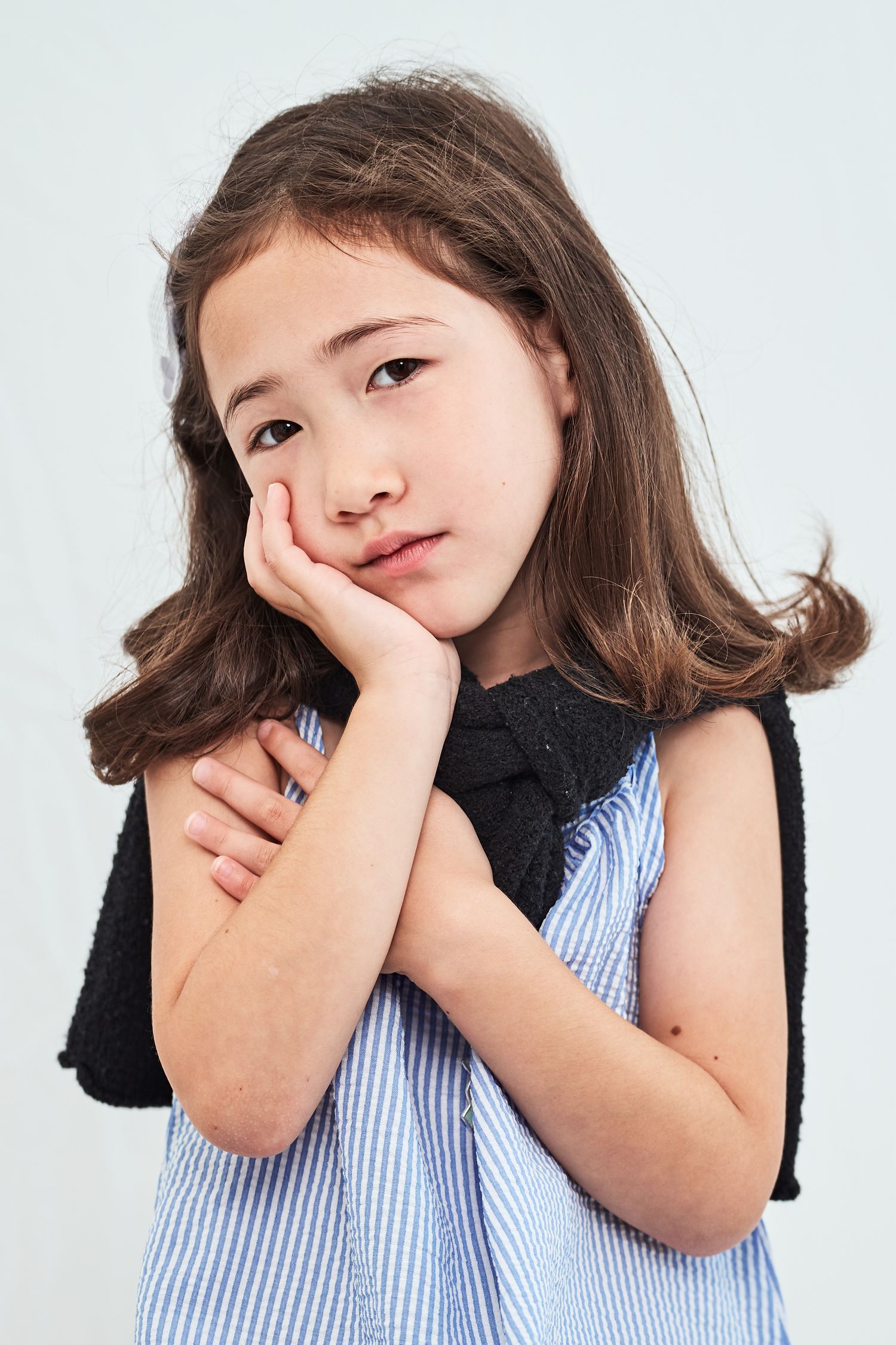 Young child in striped shirt makes playful expressions in four sequential portrait photos against white background.