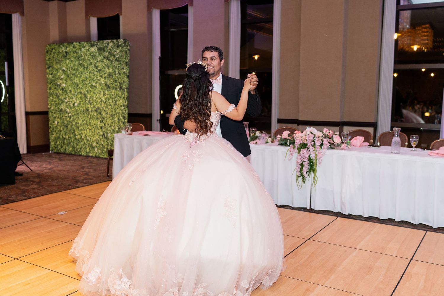 Elegant ballroom setting with couples dancing on a wooden floor under soft lighting.