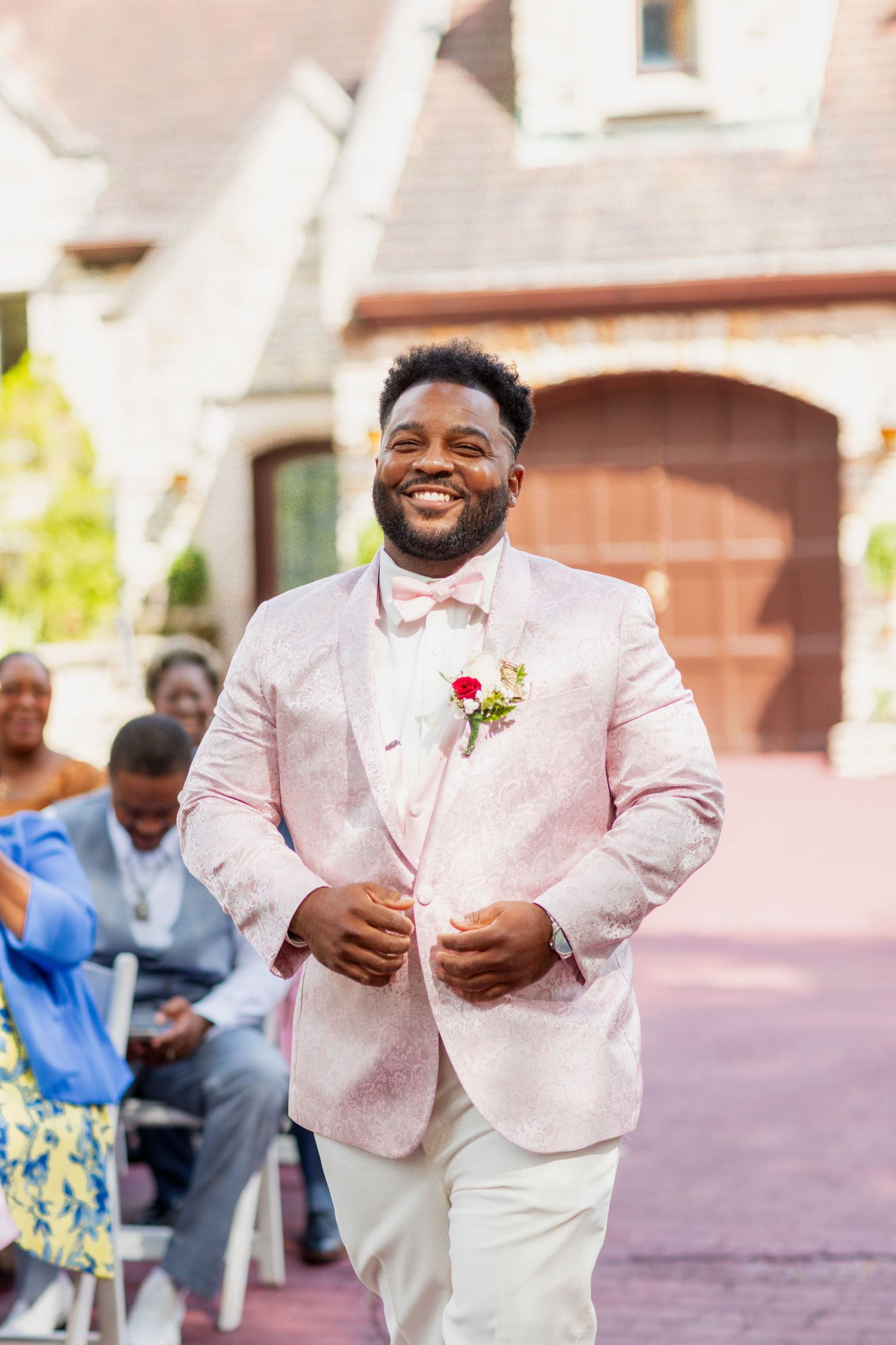 A joyful wedding ceremony moment captured in front of a brick building with arched doors.