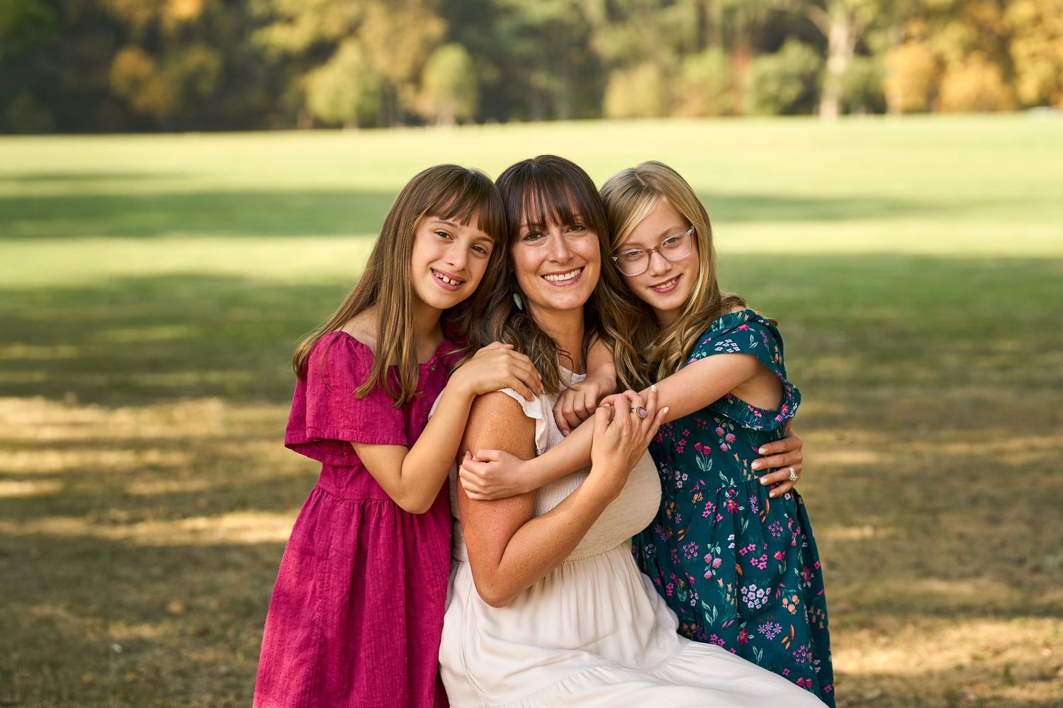 A group poses together outdoors in coordinated outfits during a golden hour photoshoot in a park setting.