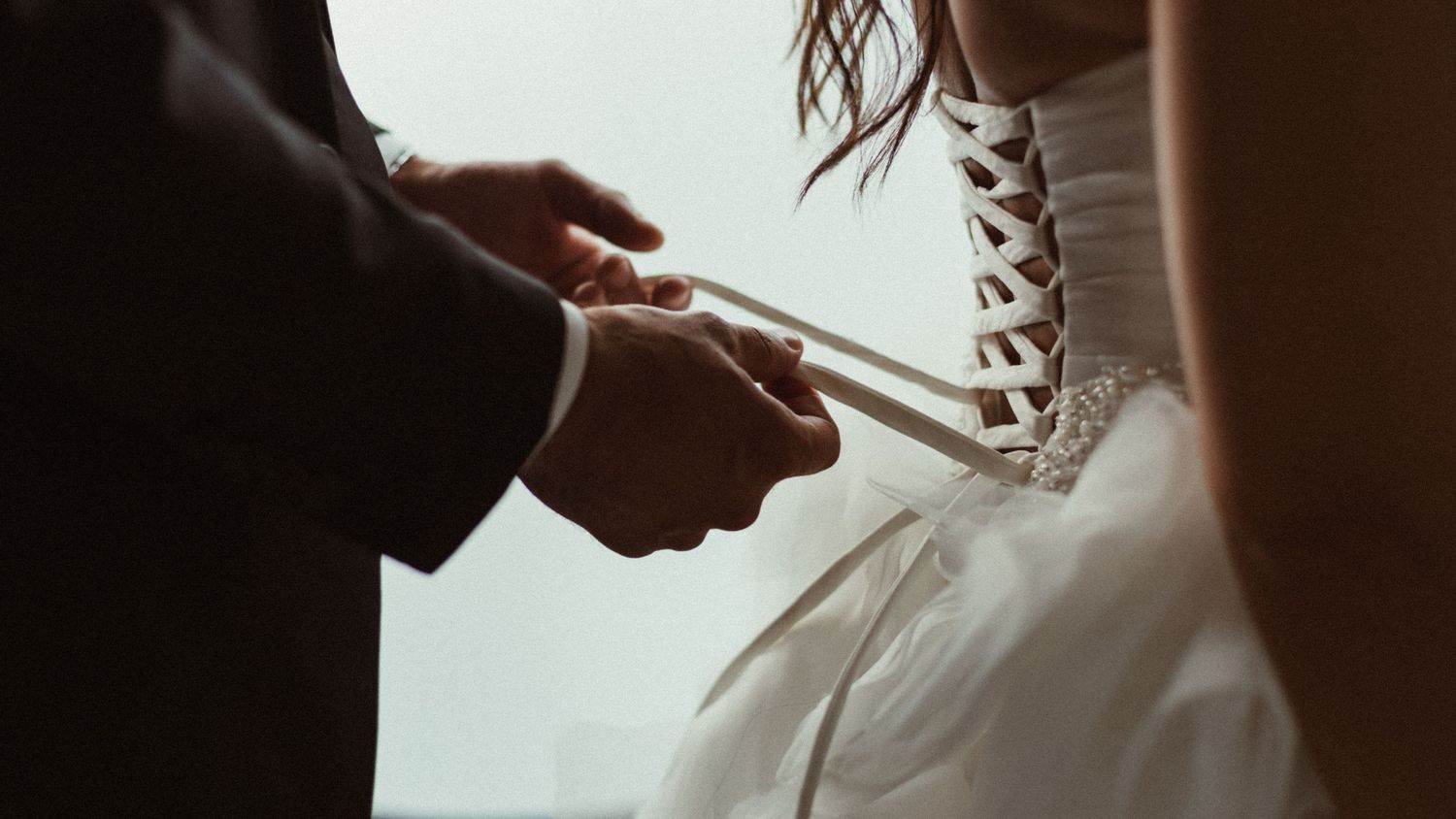 Atmospheric detail shot of wedding dress being laced up.