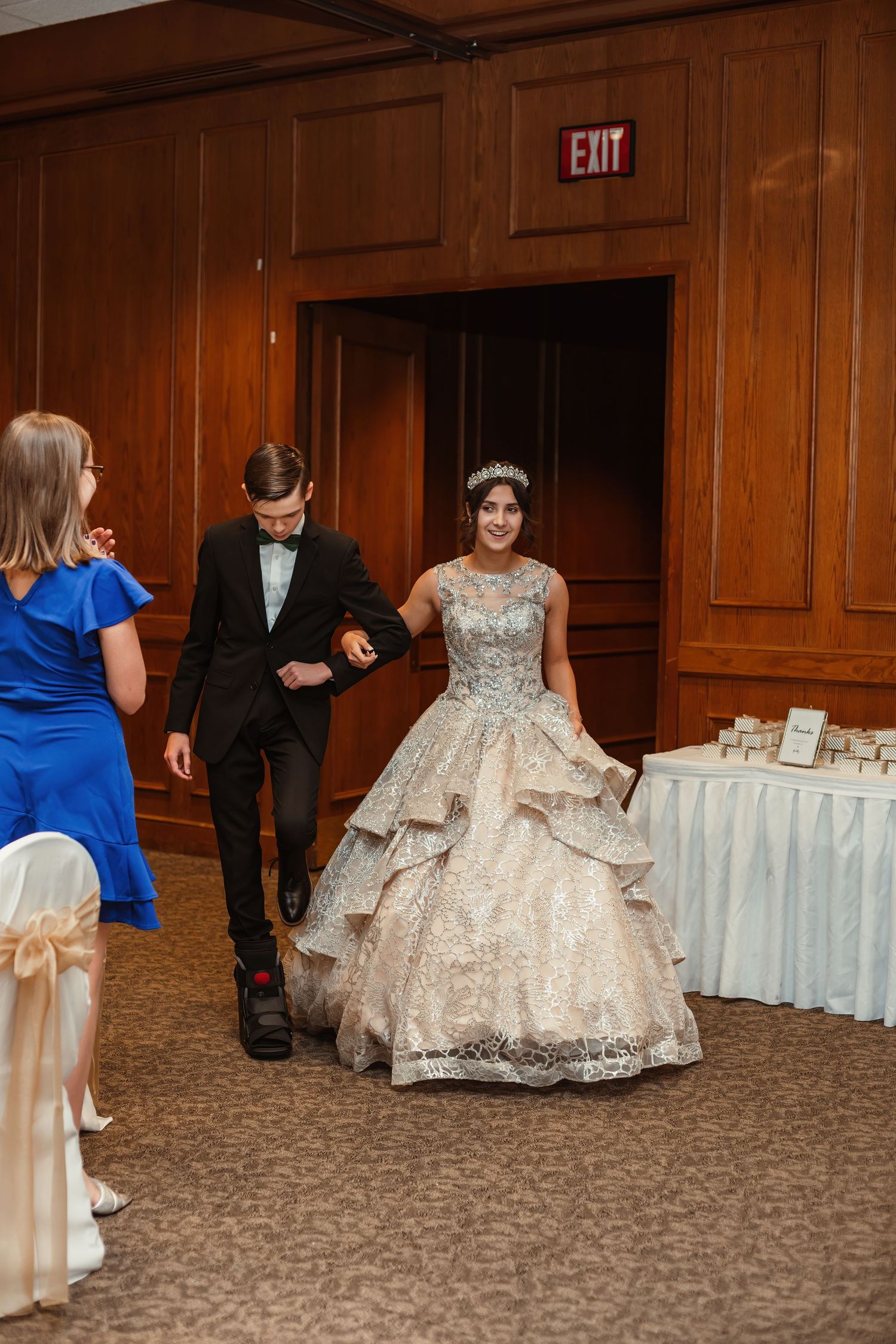 A couple makes their grand entrance into a wood-paneled reception hall.