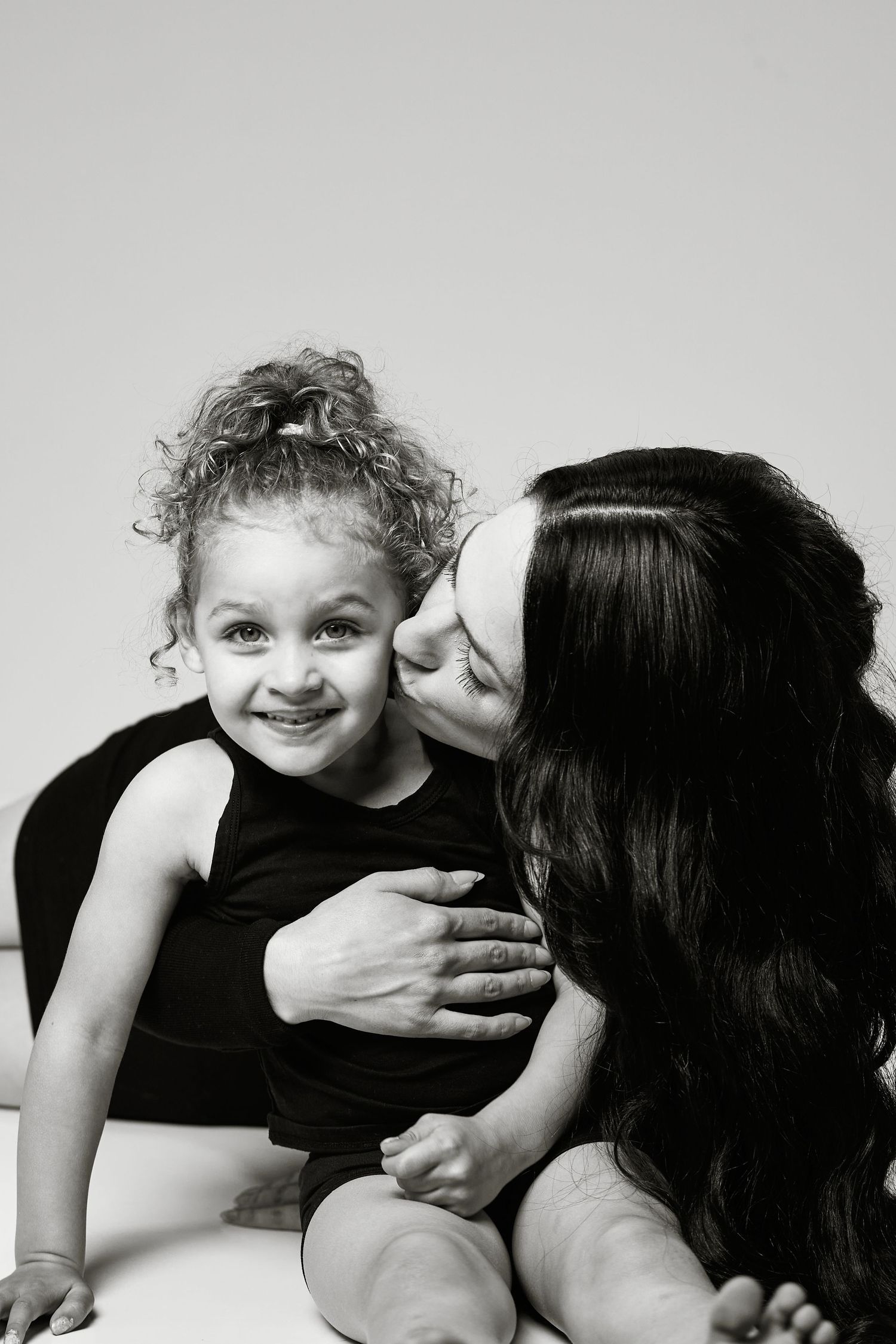 A black and white portrait of a tender mother-child moment showing affection and love between the two.