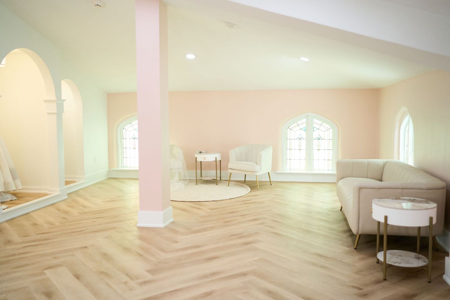 Bright modern reception space with herringbone floors, arched windows and blush pink walls.