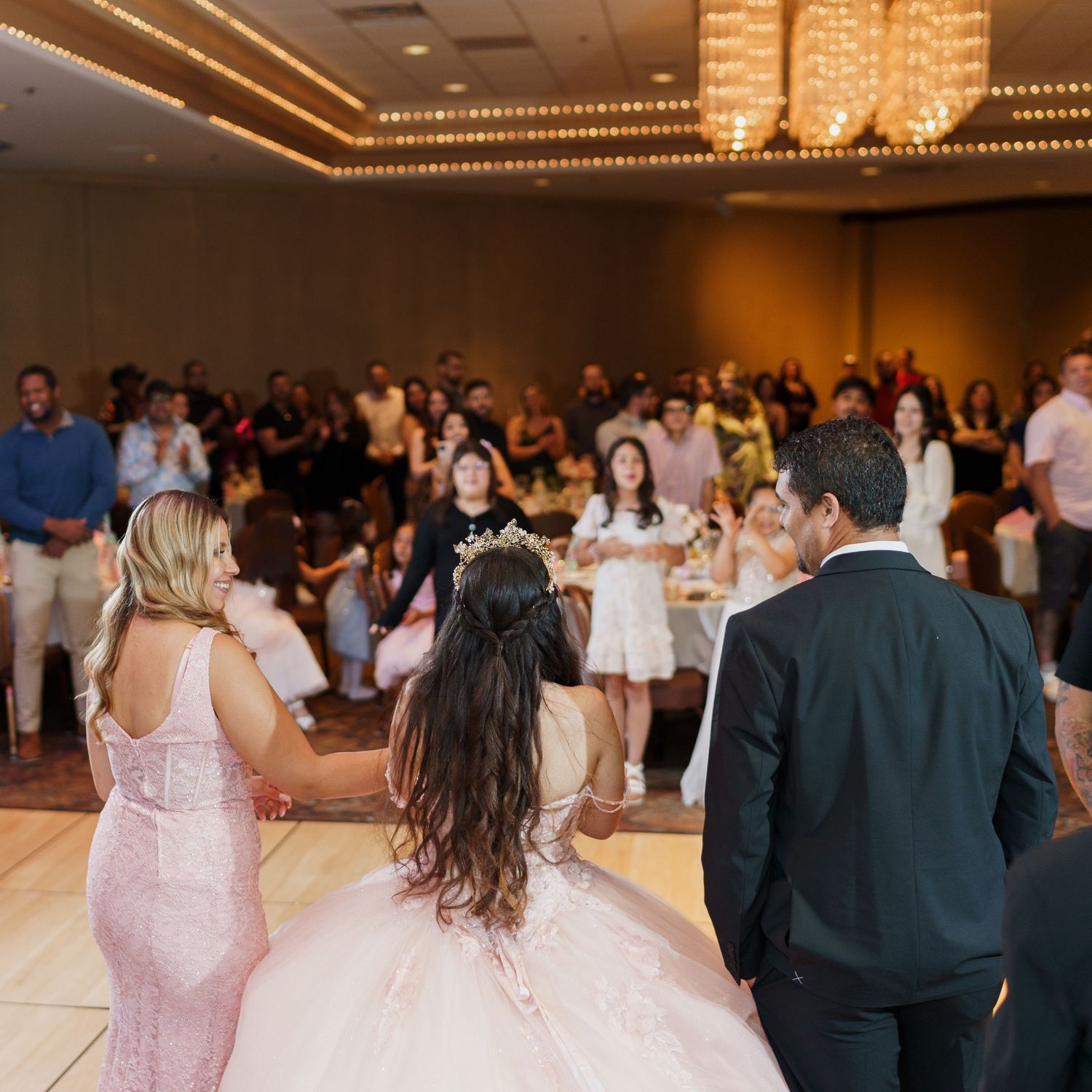 A ballroom celebration with chandeliers and guests gathered for a special event.