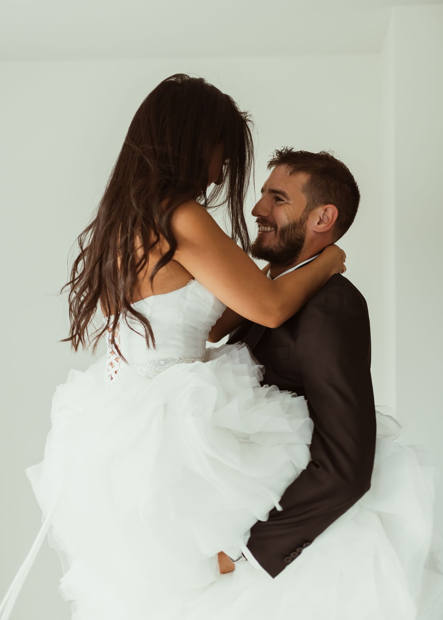 Wedding couple sharing playful moment in studio with flowing white dress.