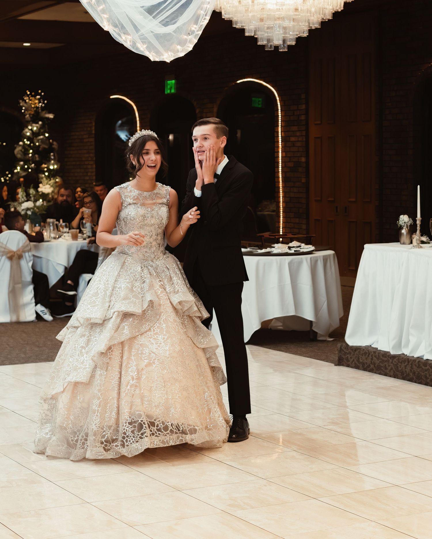 A couple shares an emotional moment during their first dance at a wedding reception in an elegantly decorated venue.
