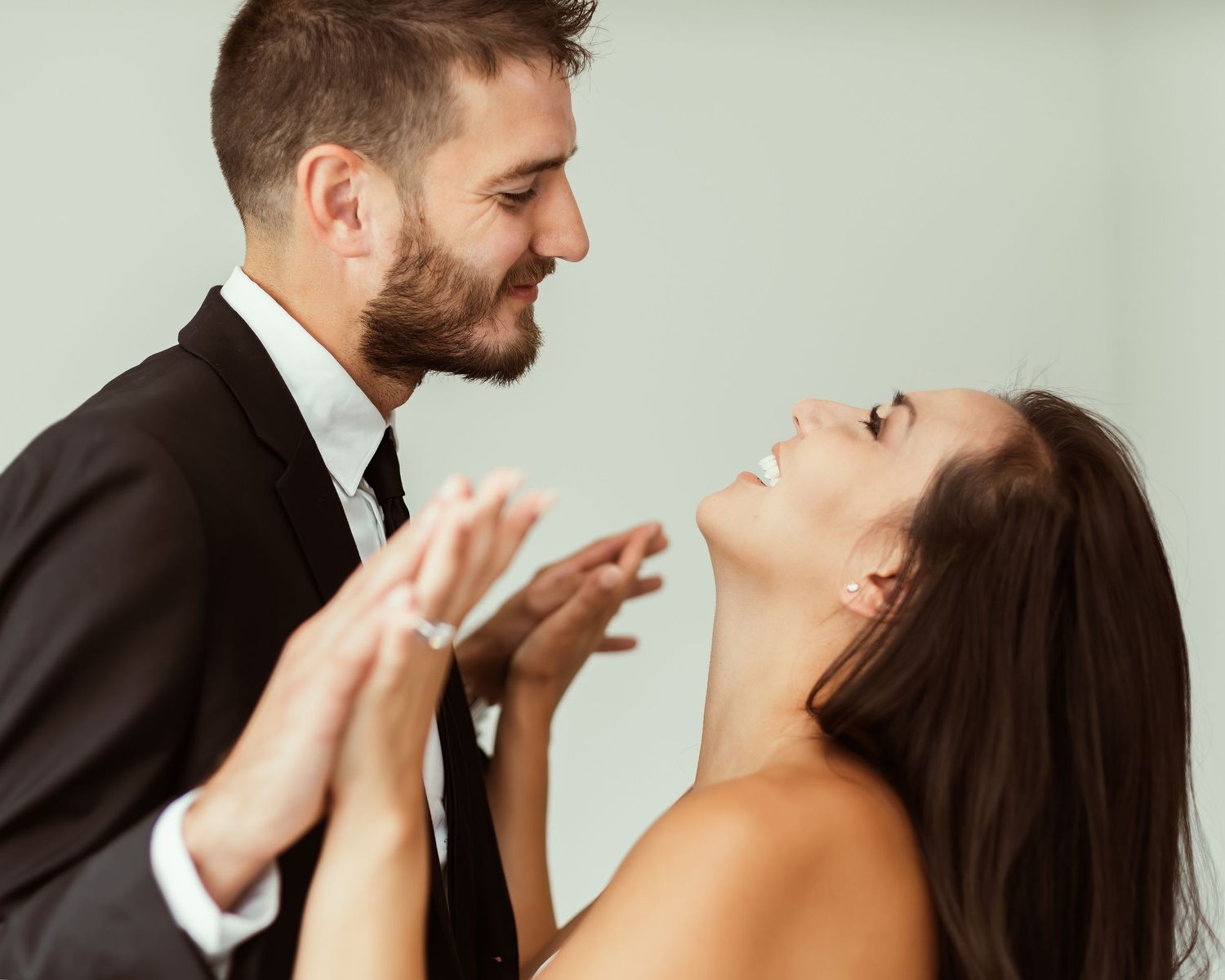 A playful wedding portrait showing a couple sharing a lighthearted moment in formal attire.