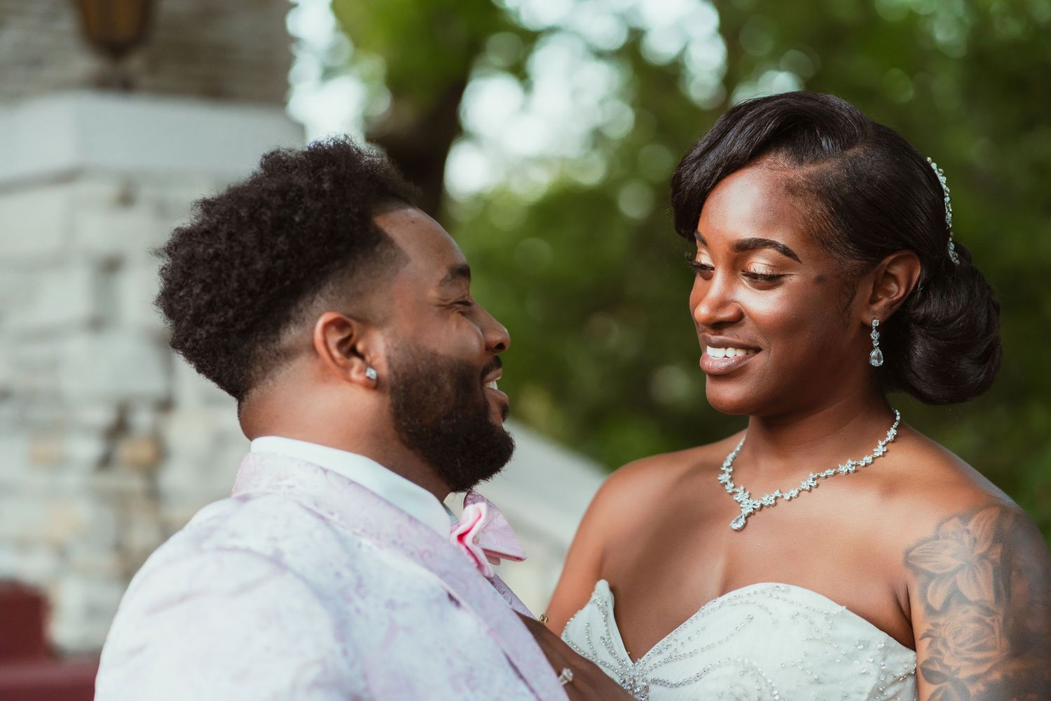 Joyful outdoor wedding moment capturing the couple's loving interaction against a stone wall backdrop.