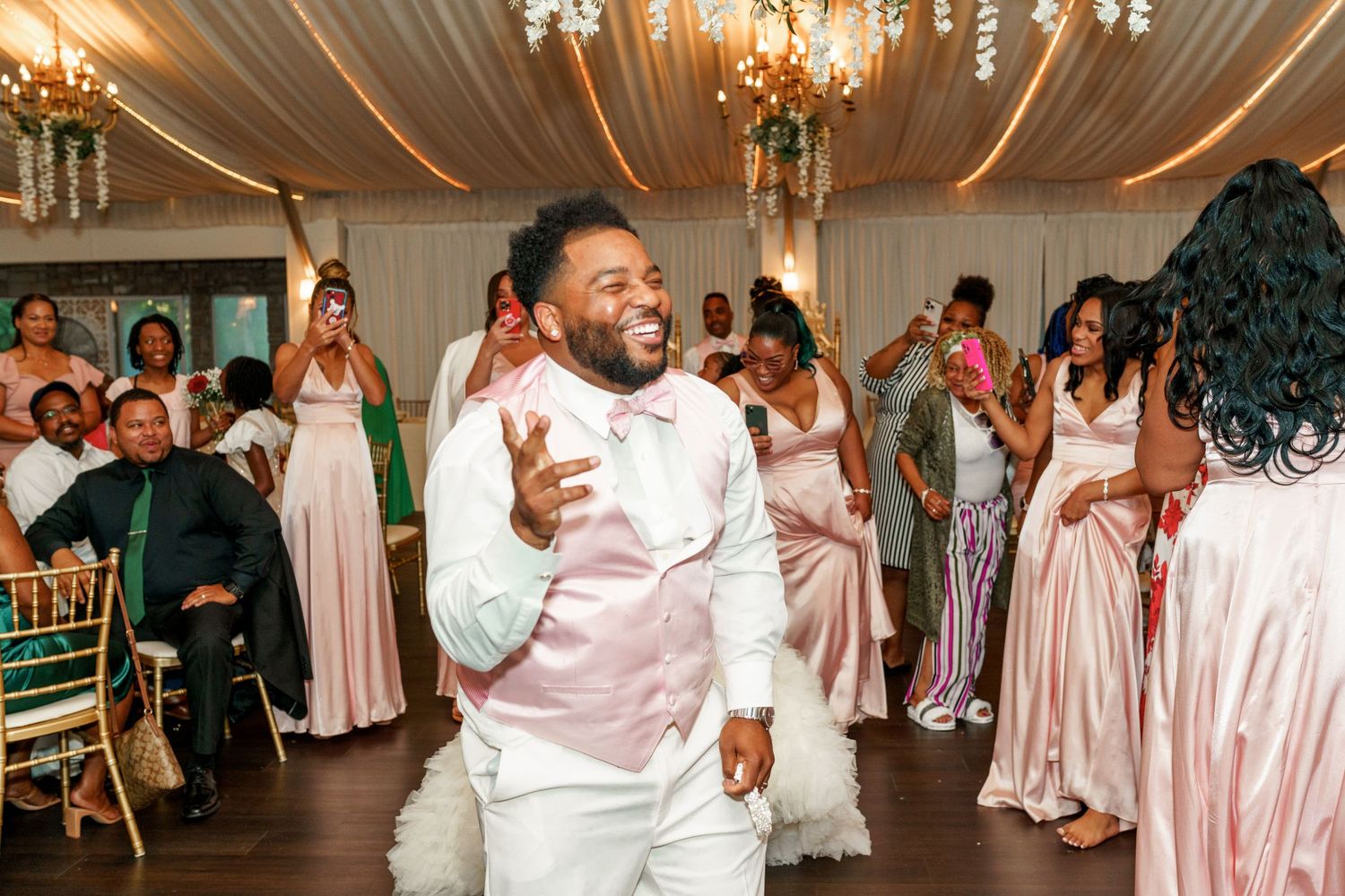 Wedding celebration features enthusiastic dancing in decorated reception venue with draped ceiling.