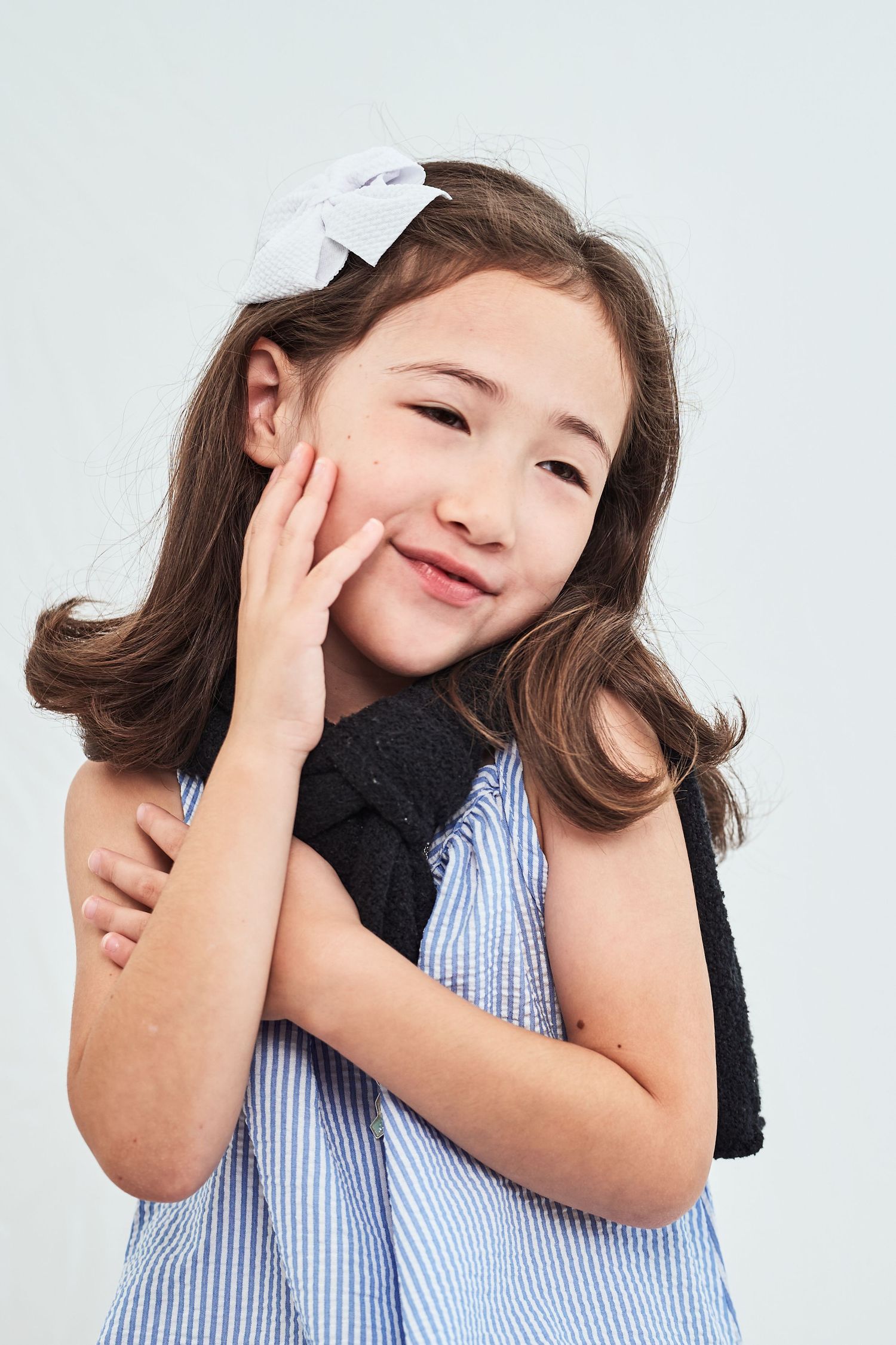 A series of four photos showing a young child in a striped dress hugging and expressing joyful emotions.