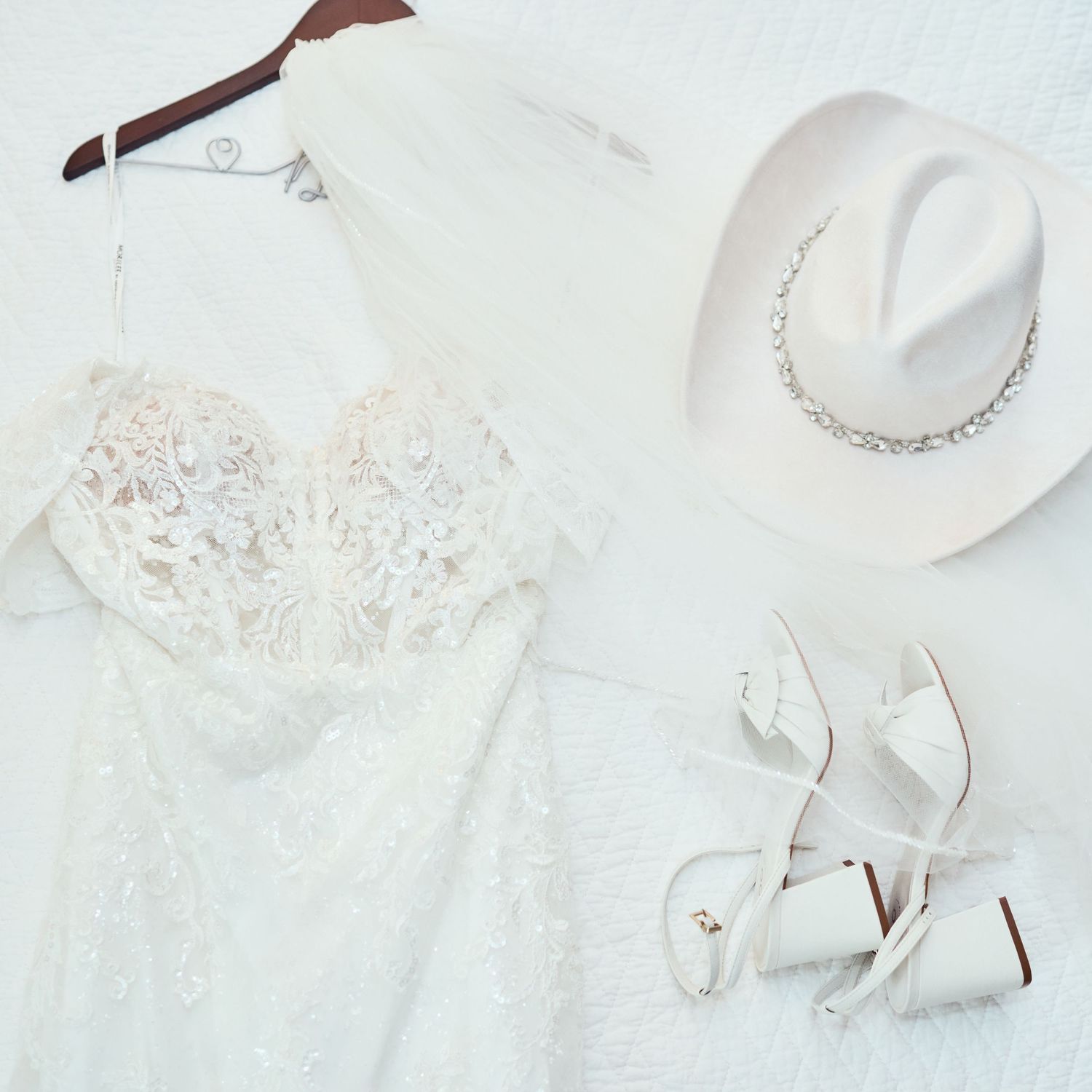 Elegant white wedding accessories including lace, pearl jewelry, and satin shoes arranged on a light background.