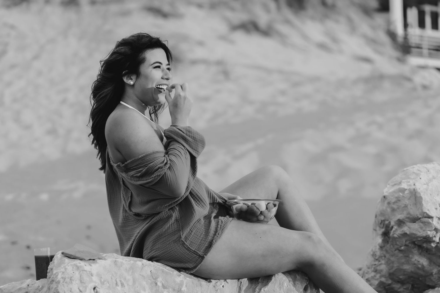 Black and white portrait of woman relaxing on beach rocks.