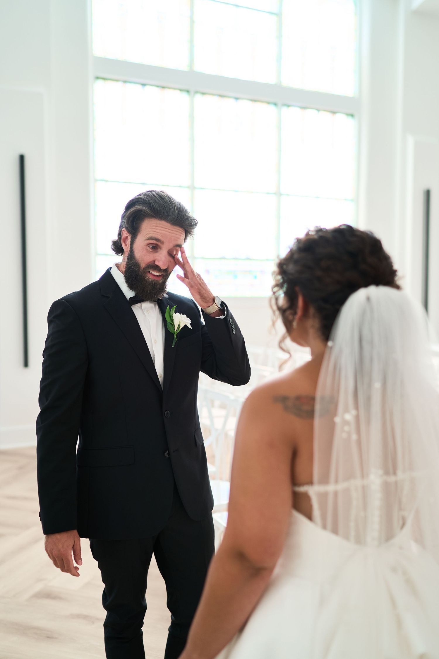 First look sequence showing emotional reactions between a bride and groom in a bright indoor setting.