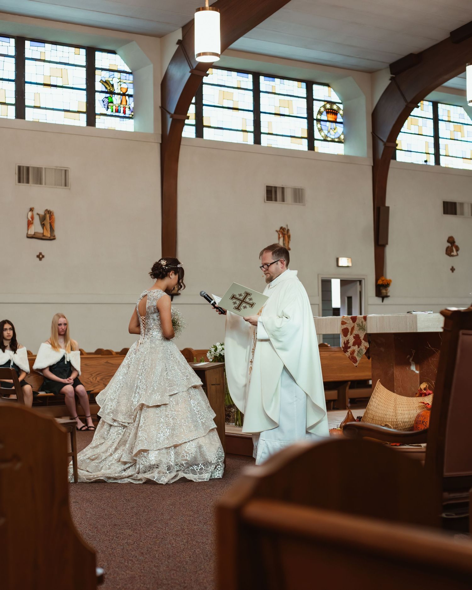 A traditional Catholic wedding ceremony taking place in a church with stained glass windows.