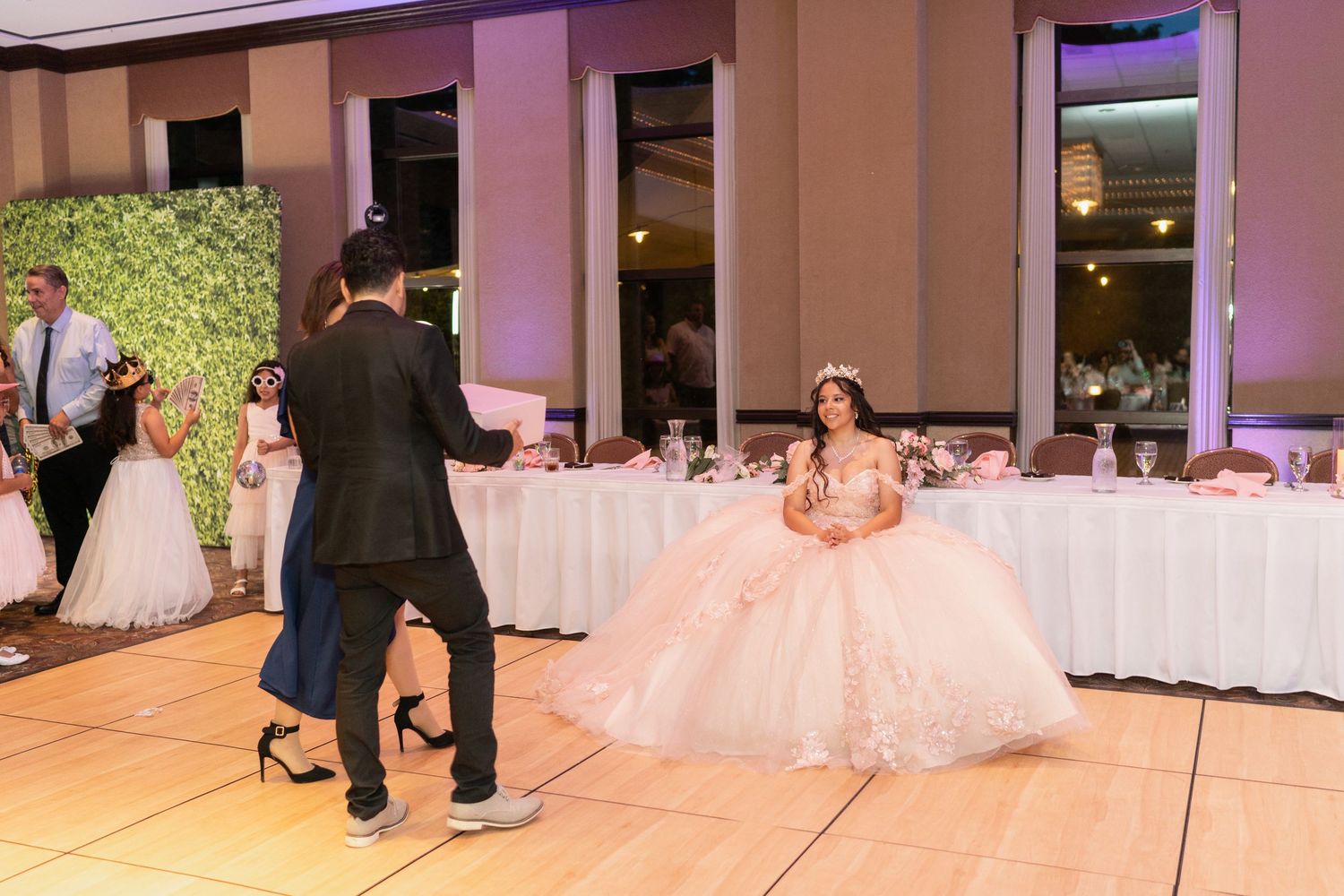 A celebration taking place in an elegant ballroom with purple lighting and white decor.
