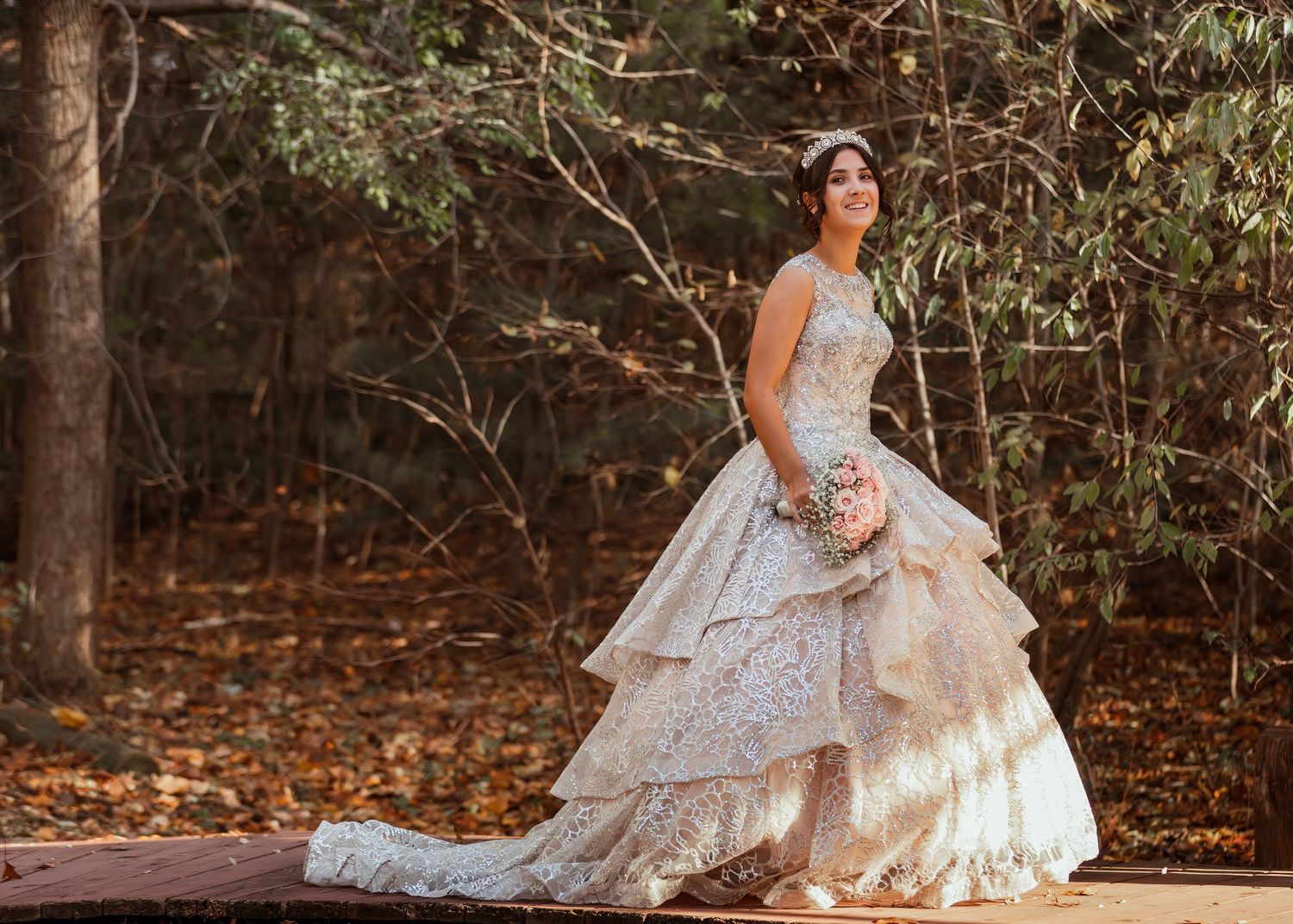 A stunning layered lace wedding gown photographed in an autumn woodland setting.