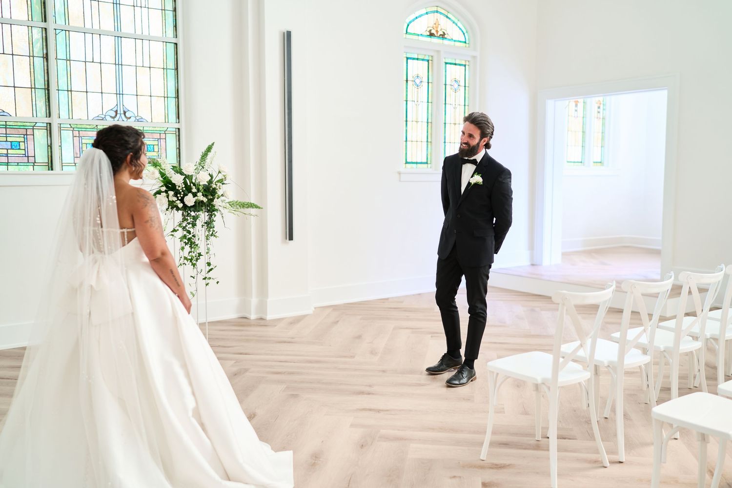 Modern church wedding ceremony setup with white chairs and floral arrangements.