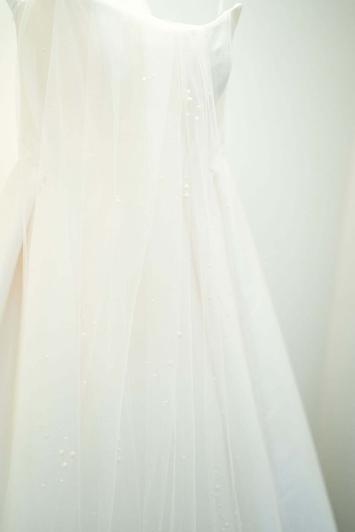 Close-up detail of delicate white wedding dress fabric with soft lighting.