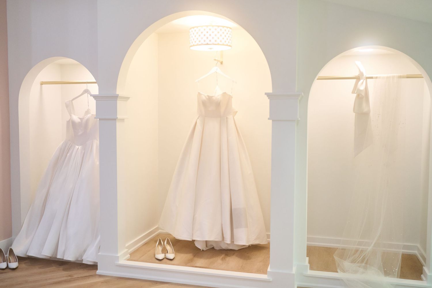 Multiple views of an elegant white wedding dress displayed in an arched alcove.