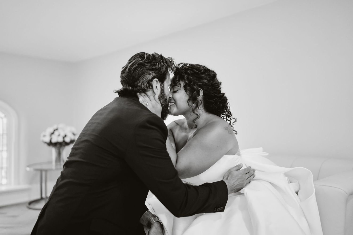 A tender black and white moment between newlyweds sharing an intimate kiss.