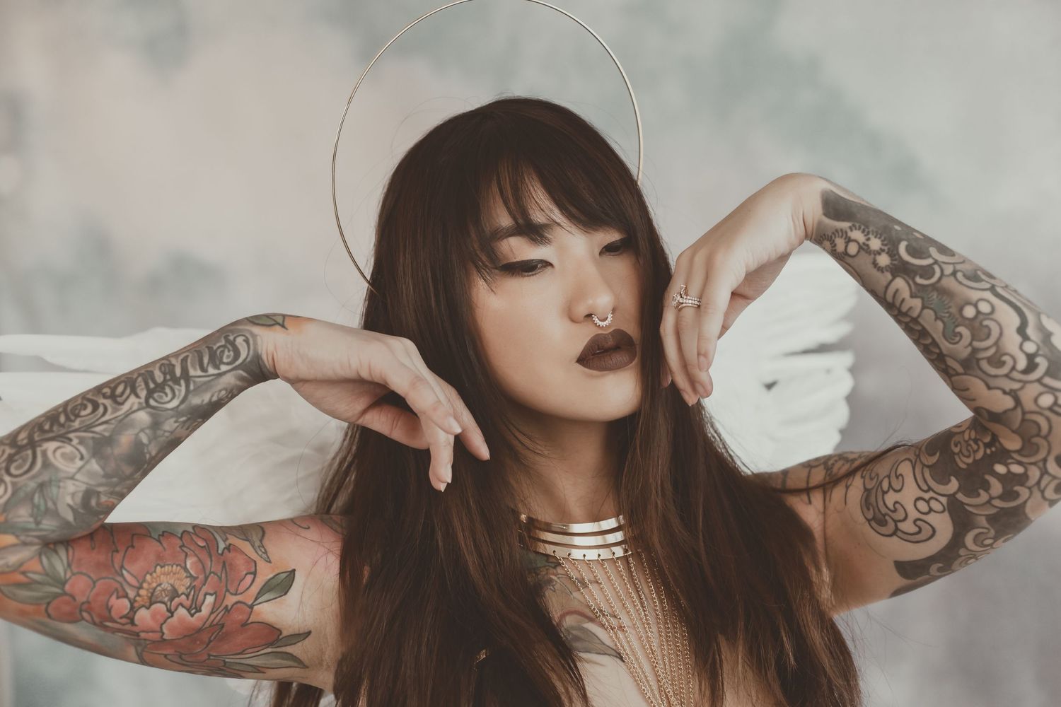 Dramatic portrait with halo effect and tattoo details in ethereal lighting.