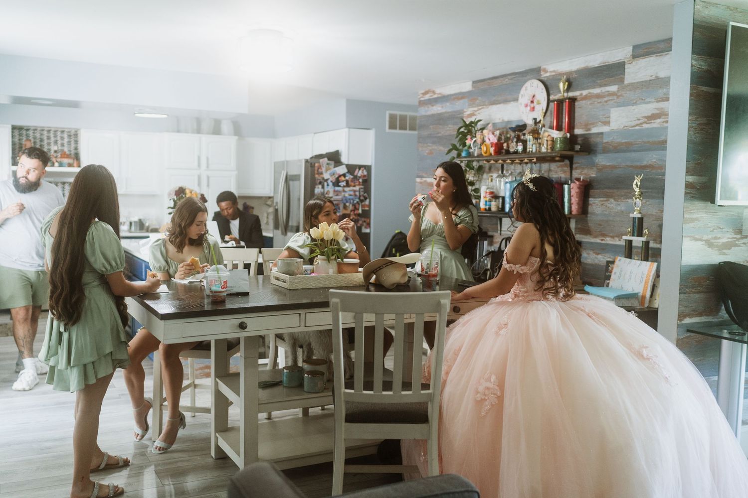 Getting ready scene with bridesmaids and quinceanera dress in a modern room.