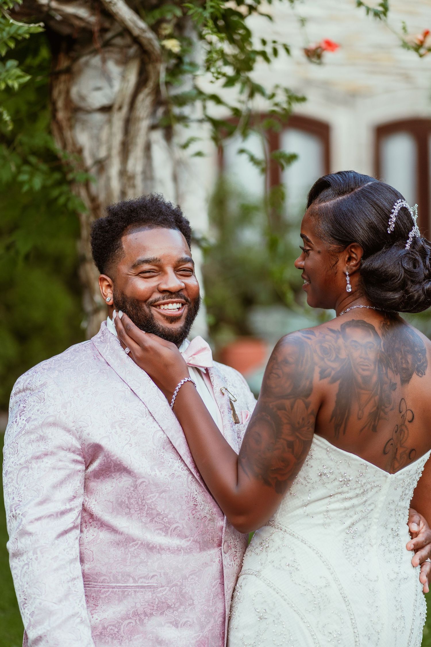 A joyful wedding moment captured as couple shares laughter in a garden setting.