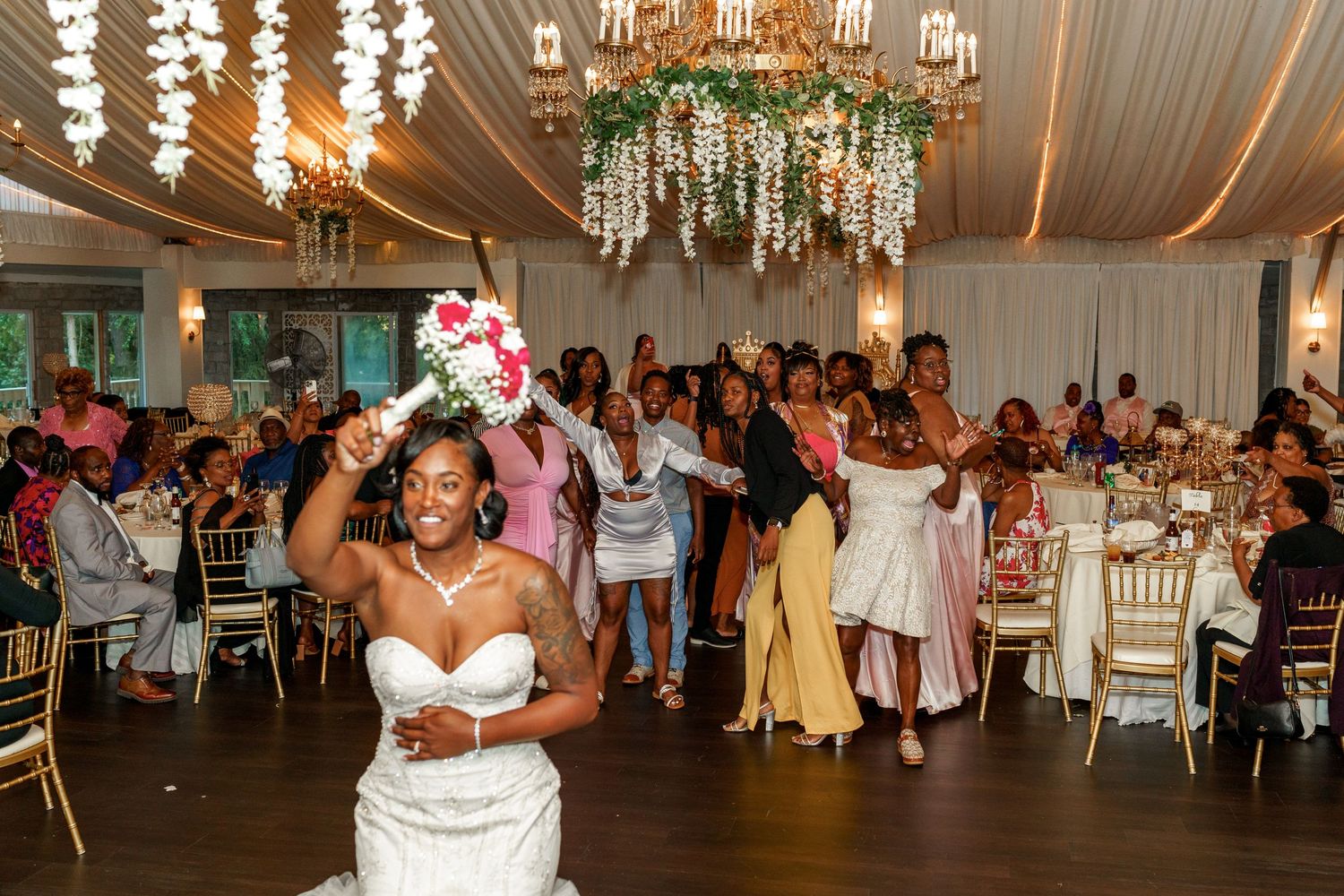 Wedding reception dance party with decorative chandelier and draped ceiling details.