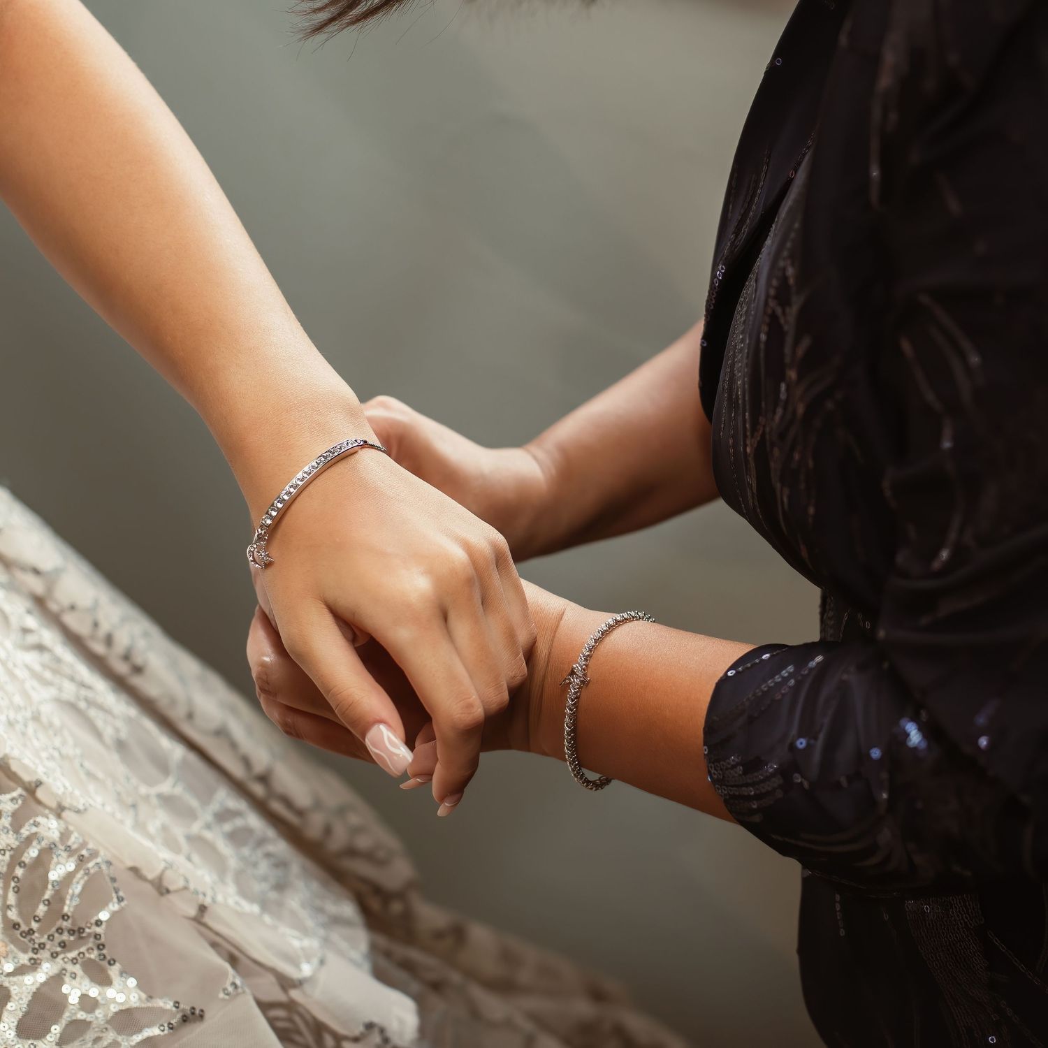 Close-up of hands wearing delicate bracelets during a wedding preparation moment.