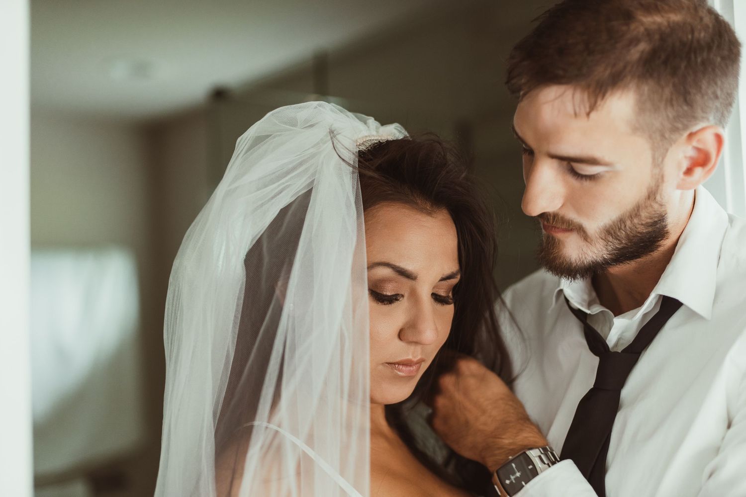 Intimate wedding portrait showing tender moment between couple with bride wearing delicate veil.
