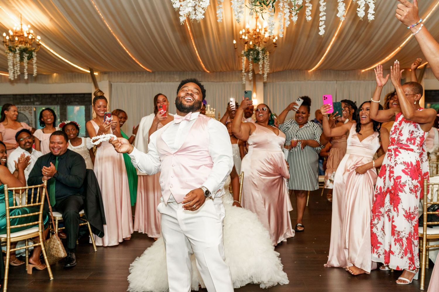 Wedding reception features joyful dancing and celebration under elegant chandeliers.