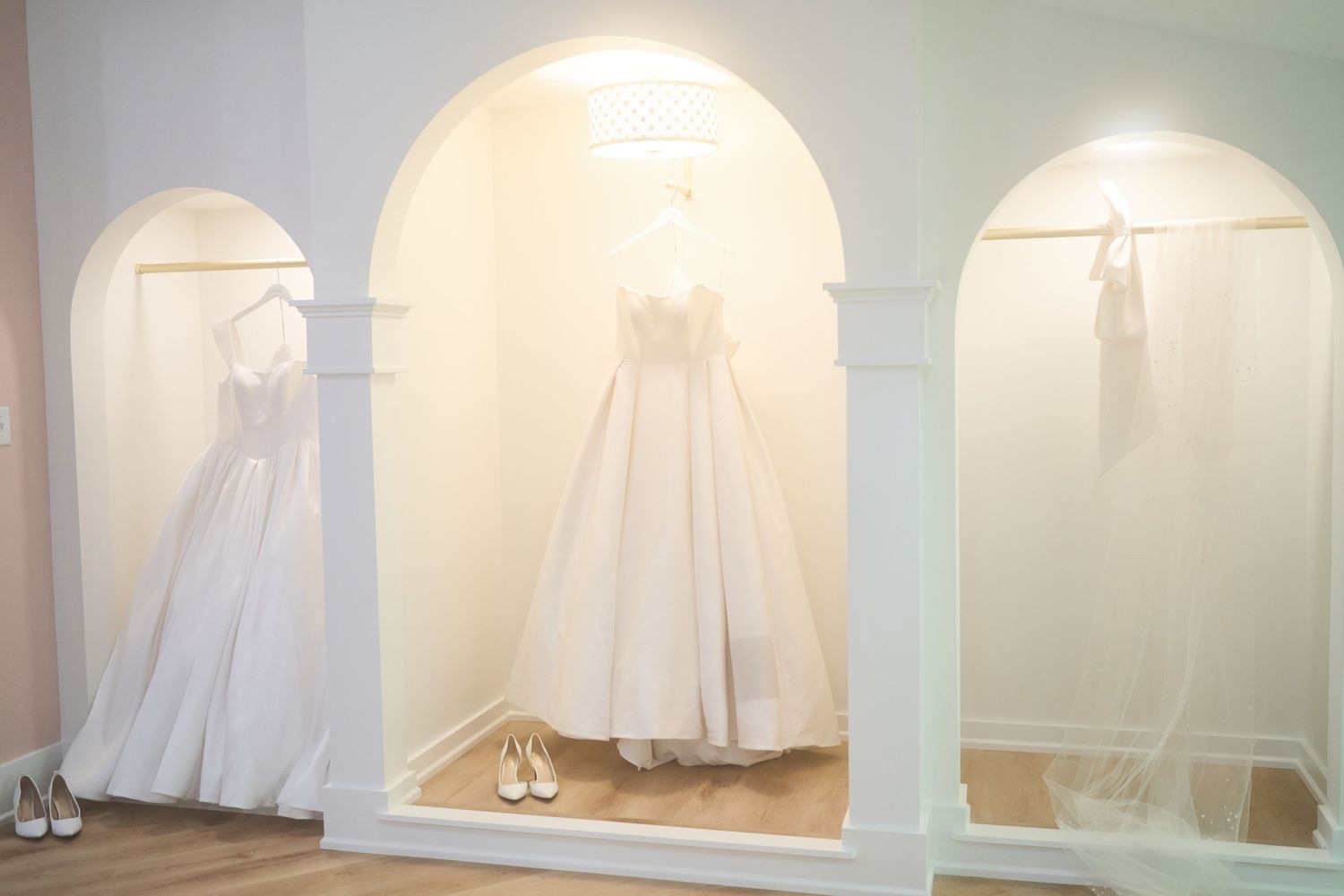 Three elegant white wedding gowns, from Something Blue Bridal, displayed in the bridal suite at Kaleidoscope wedding venue in Pierceton, IN