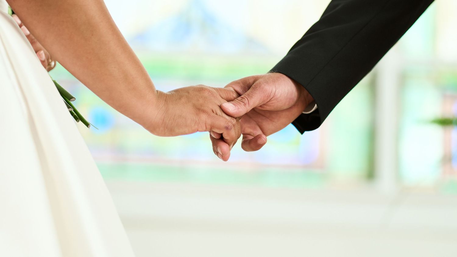 Close-up of a bride and groom holding hands during their wedding ceremony.