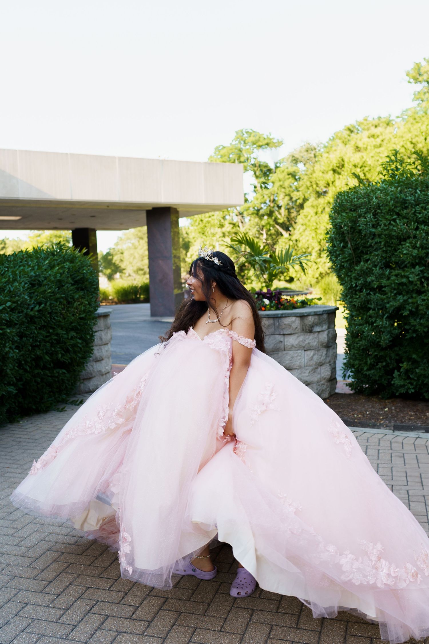 A flowing pink ballgown with tulle skirt photographed outdoors on a stone pathway.
