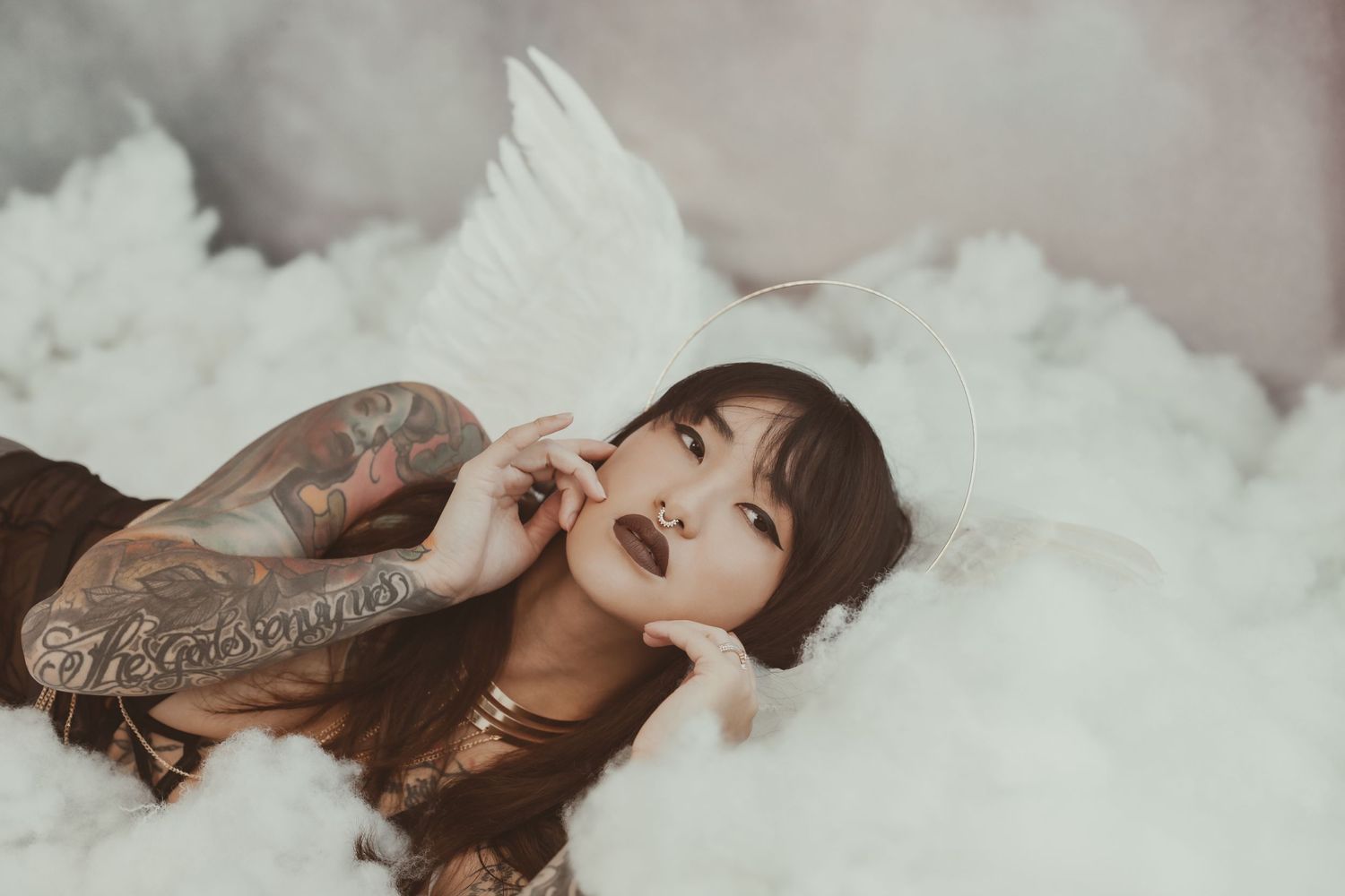 An atmospheric portrait of a model with dark makeup reclining in cloud-like white fabric.