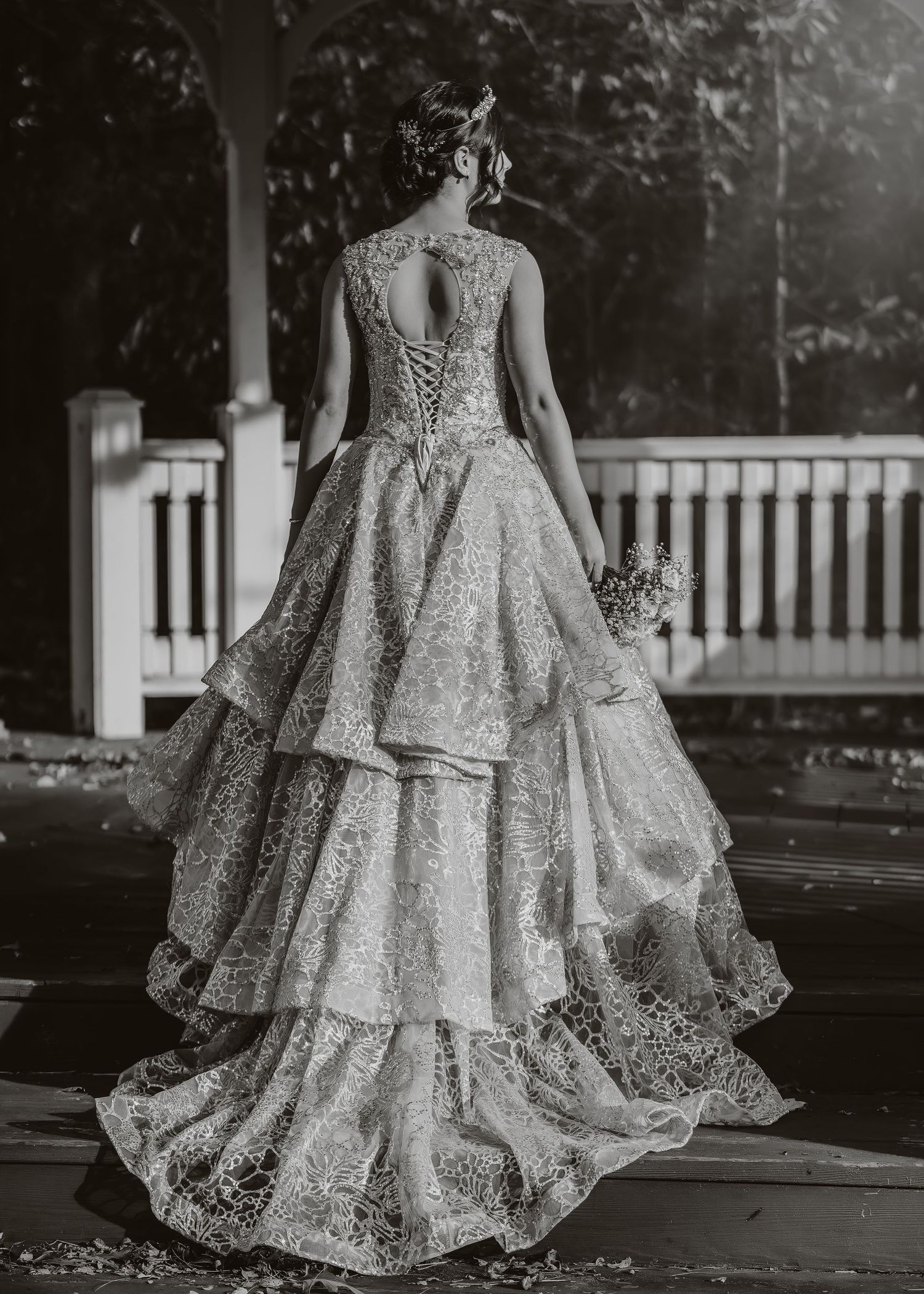 Black and white photo of a tiered lace wedding gown with intricate back detail and train.