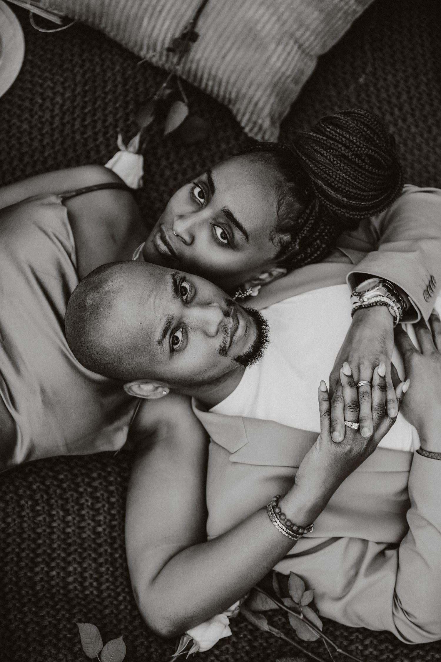 Black and white overhead shot of a couple laying together on textured fabric.